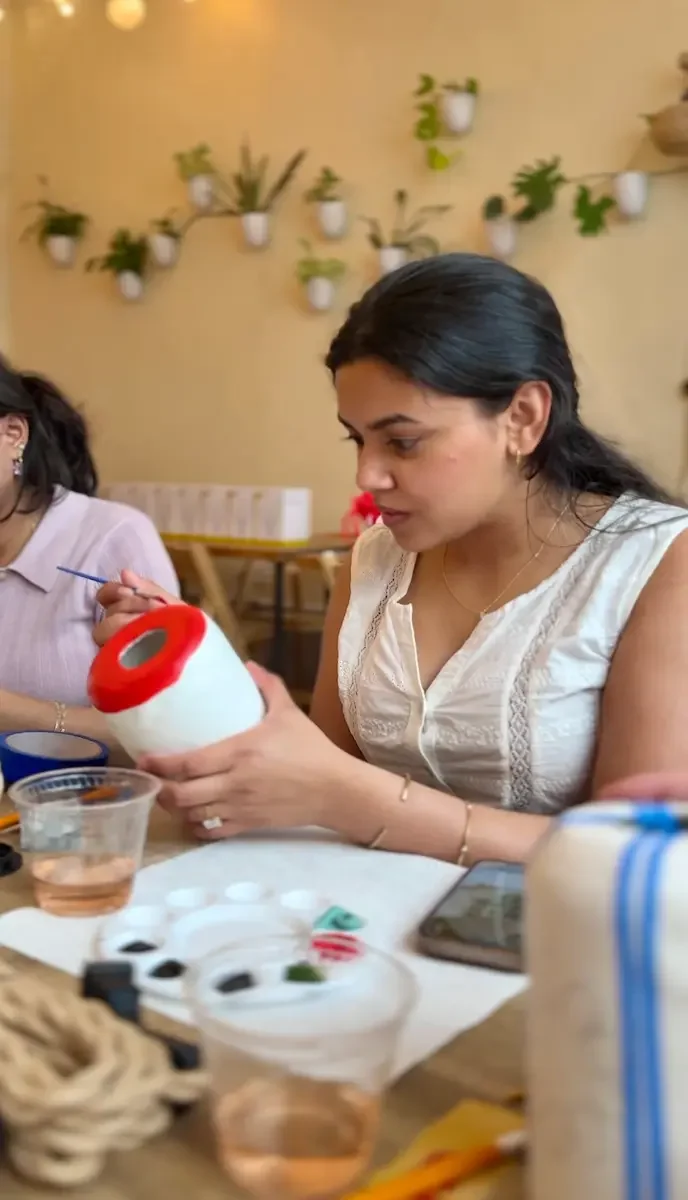 A guest painting a bold red rim around the top of a ceramic lamp base.