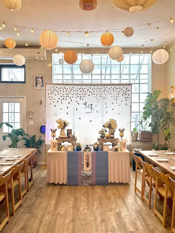 Traditional Korean Doljabi ceremony table setup at Bat Haus in Brooklyn, featuring decorative backdrop, symbolic items, and long wooden tables for a first birthday celebration.