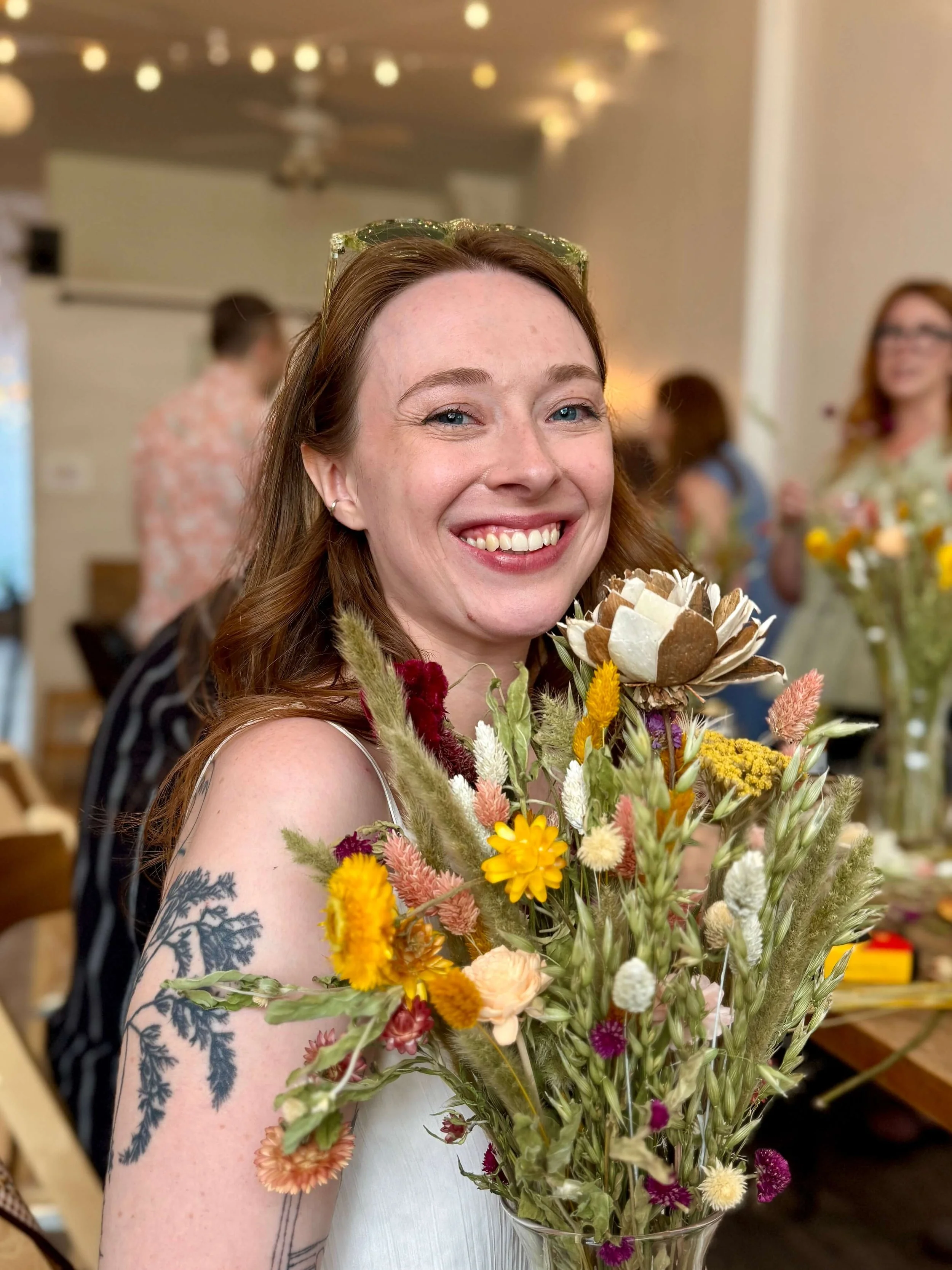 Smiling bride holding her custom flower arrangement during a bridal shower floral workshop in Brooklyn at Bat Haus.