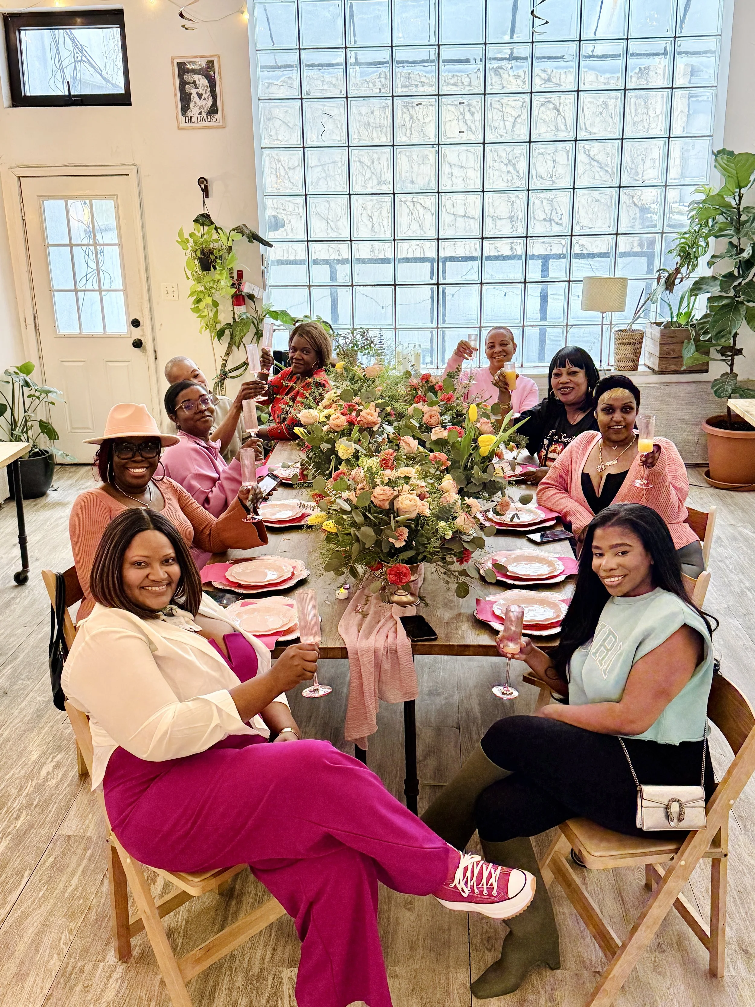 Guests celebrating a birthday party at Bat Haus in Williamsburg Brooklyn, seated at a long table with seasonal floral centerpieces and champagne, private event space for up to 50 guests.