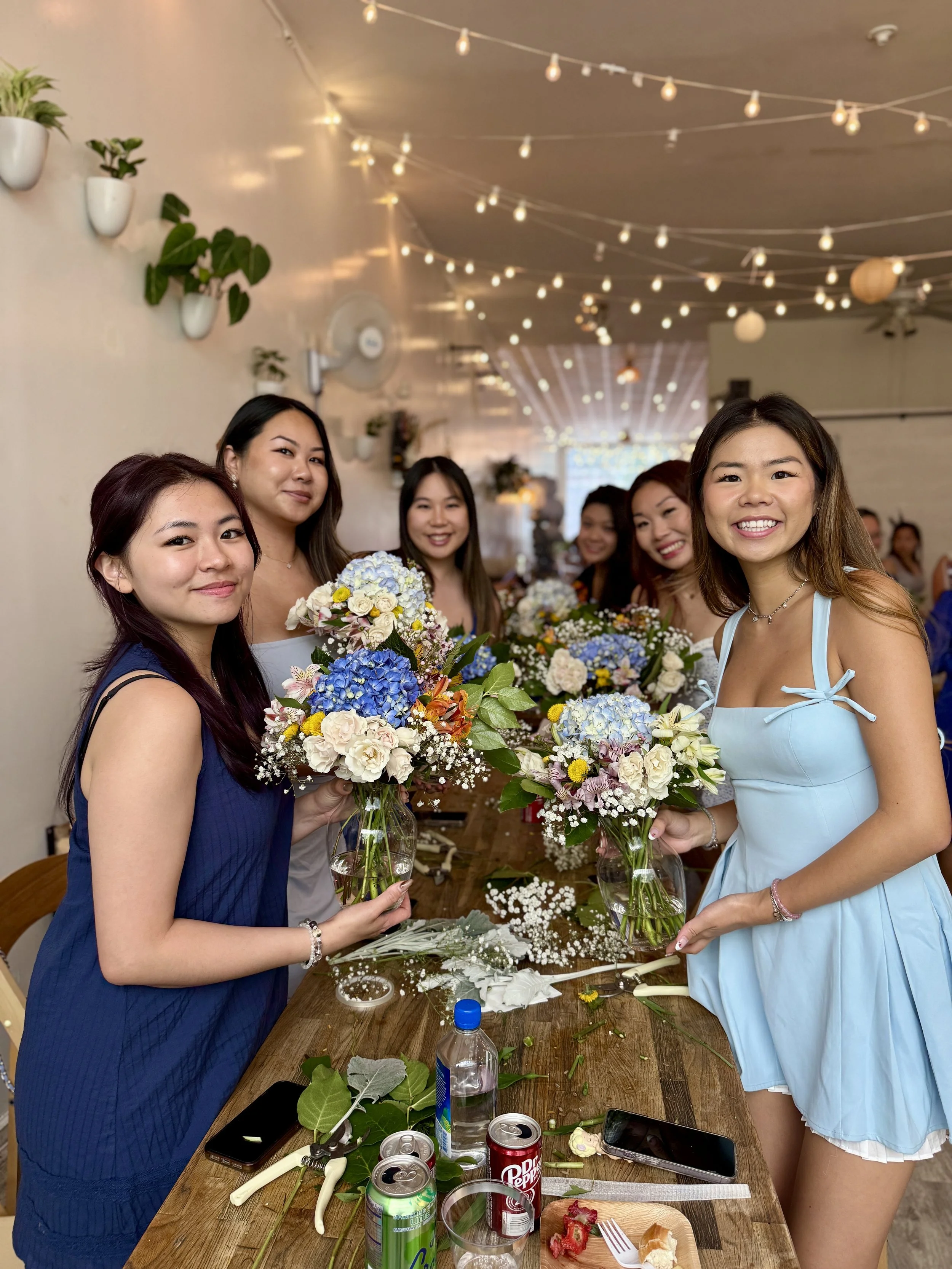 Group of women holding hand-tied bouquets with hydrangeas and roses during a floral workshop experience at Bat Haus in Williamsburg Brooklyn.
