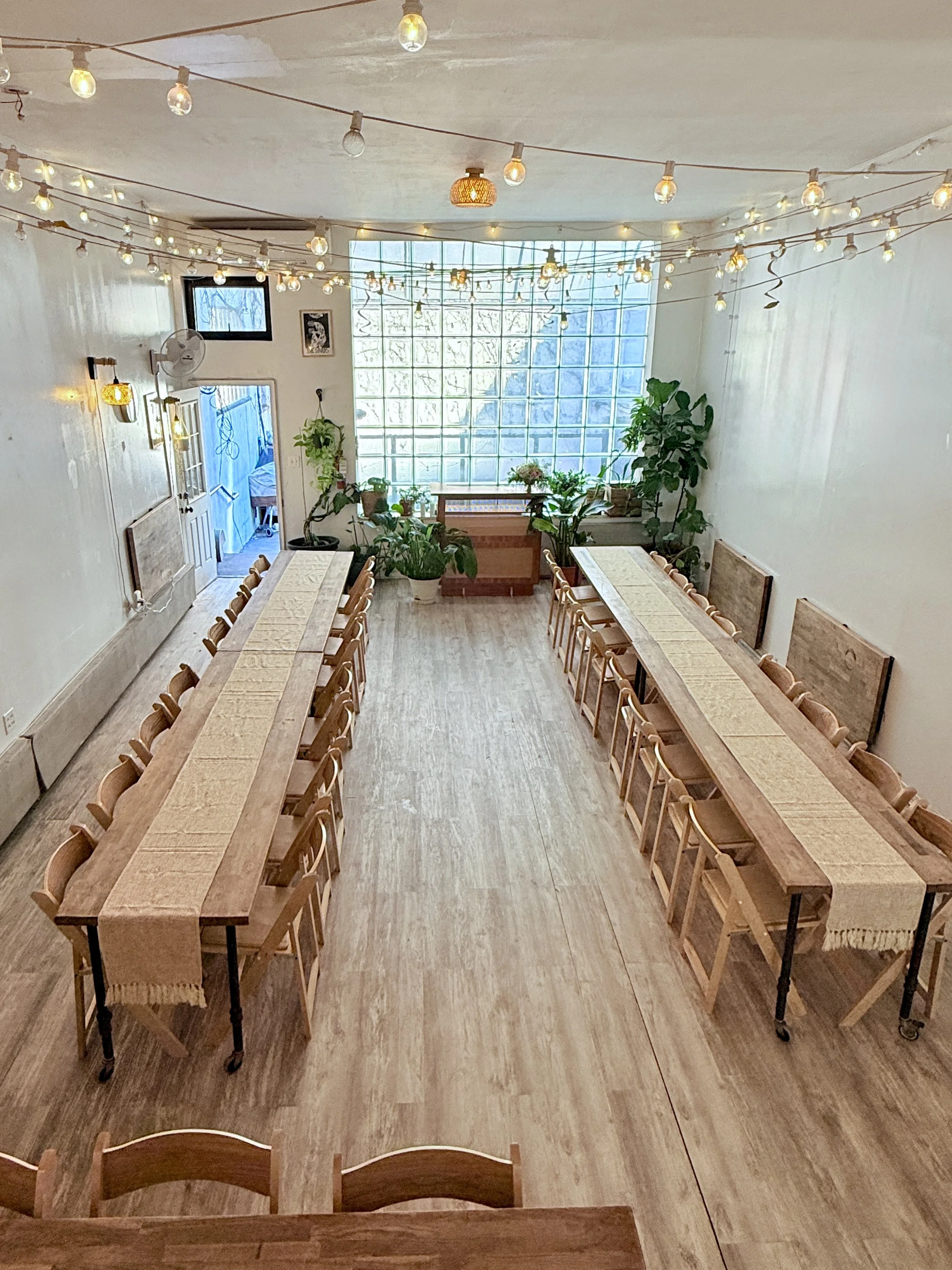 Light-filled Bat Haus event space in Brooklyn set up with long wooden tables for baby showers, weddings, engagement parties, and corporate offsite events.
