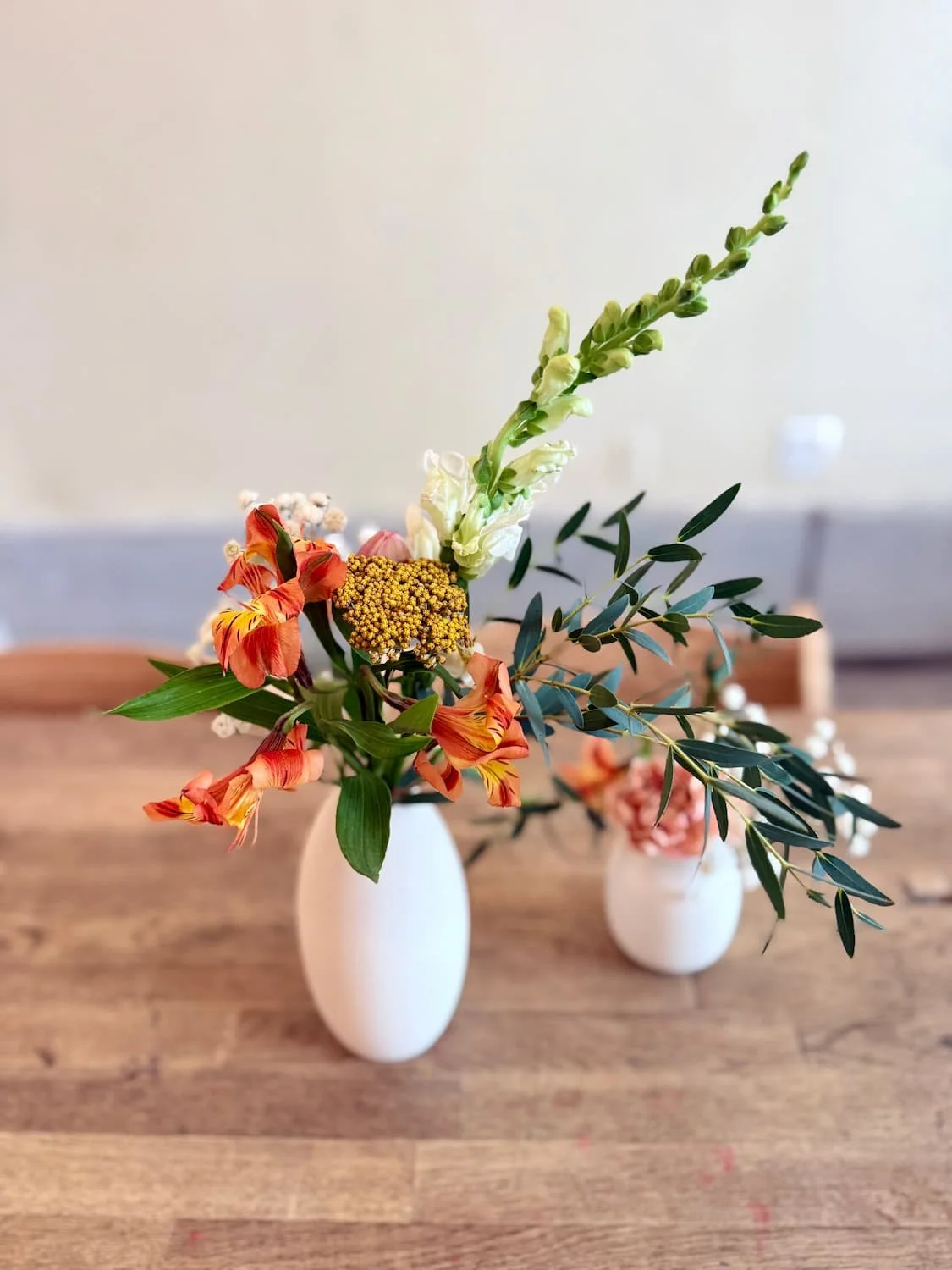 Warm autumn bud vase florals with alstroemeria and olive branch in white ceramic vases at Bat Haus in Brooklyn.