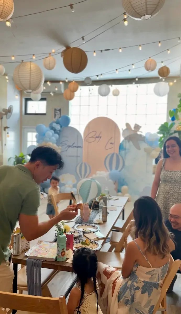 Guests celebrating beside a balloon backdrop at a baby shower at Bat Haus event space in Williamsburg, Brooklyn.