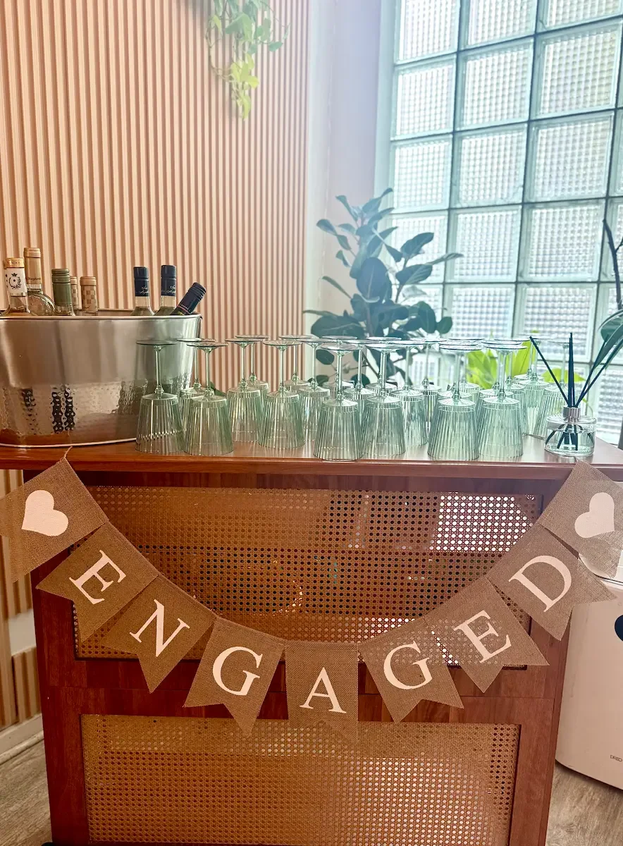 Self-serve bar with glassware and an 'Engaged' banner set up for a BYO engagement party at Bat Haus in Williamsburg, Brooklyn.