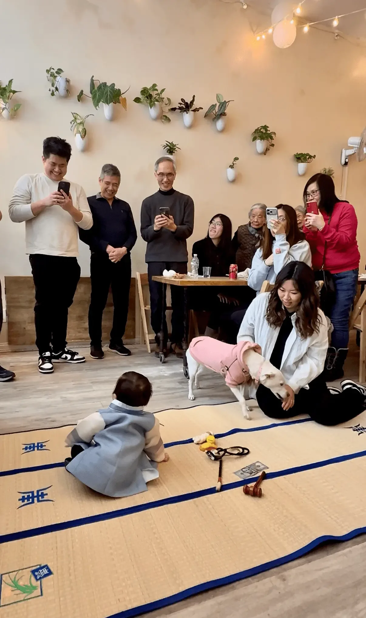 Baby crawling on a mat during a first birthday doljanchi as family gathers and takes photos at Bat Haus in Brooklyn