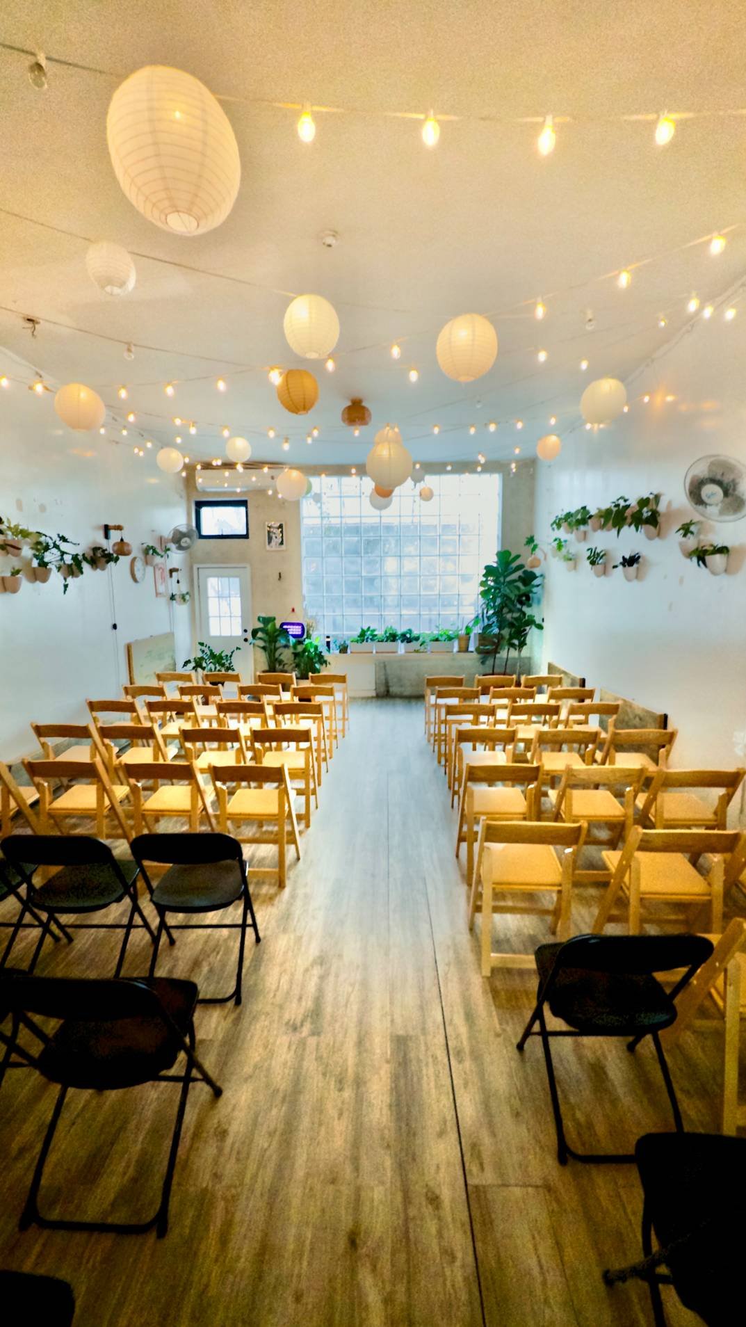 A decorated indoor event space with rows of chairs, paper lanterns and warm lighting for a micro-wedding ceremony or gathering at bat haus event space in brooklyn.