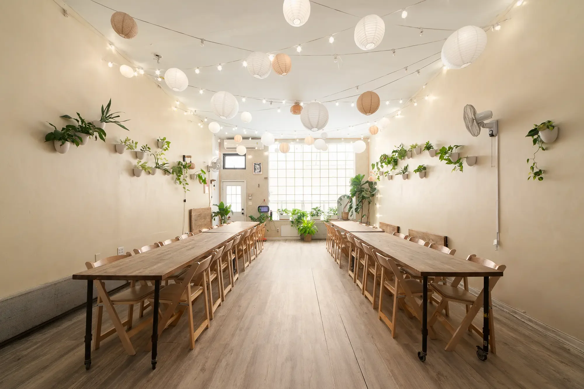 Long banquet tables under string lights and paper lanterns in the main room at Bat Haus, a Brooklyn holiday party venue for teams and groups of up to 50