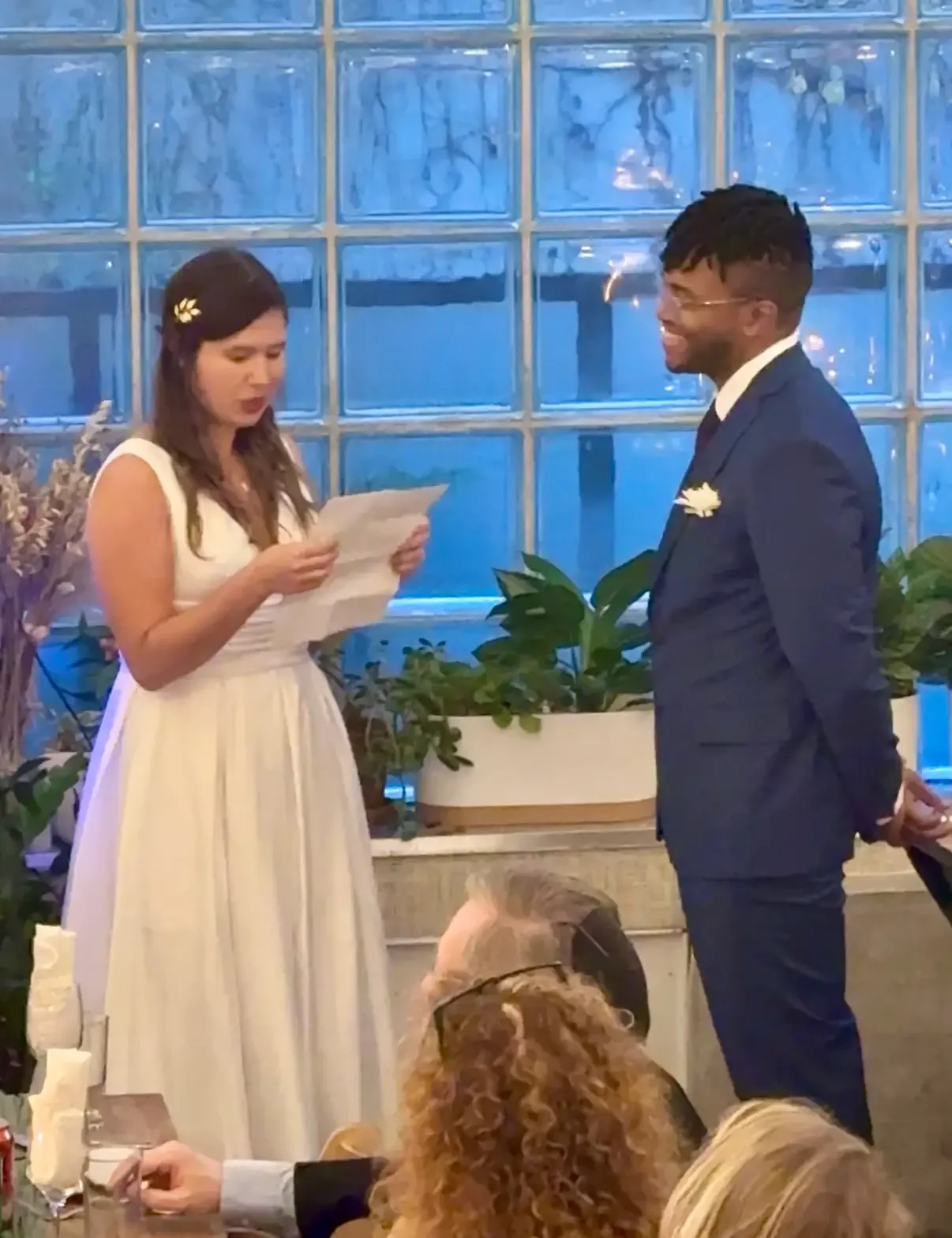 A couple exchanging vows by the glass-block window at a small wedding ceremony at Bat Haus in Brooklyn.