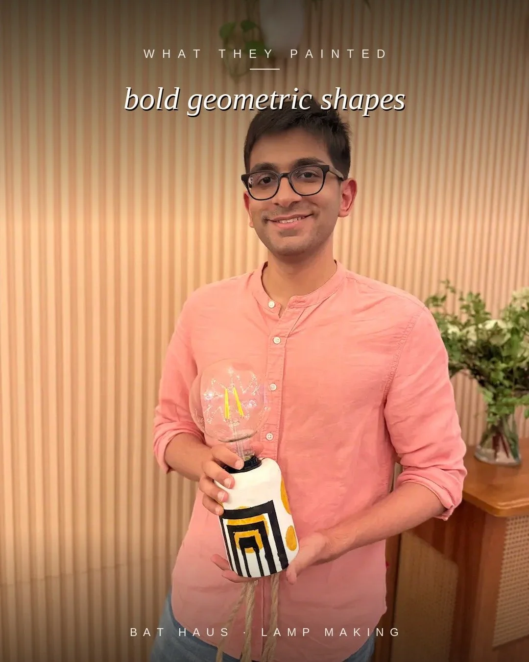 Man holding a handmade lamp painted with bold black and gold geometric shapes.