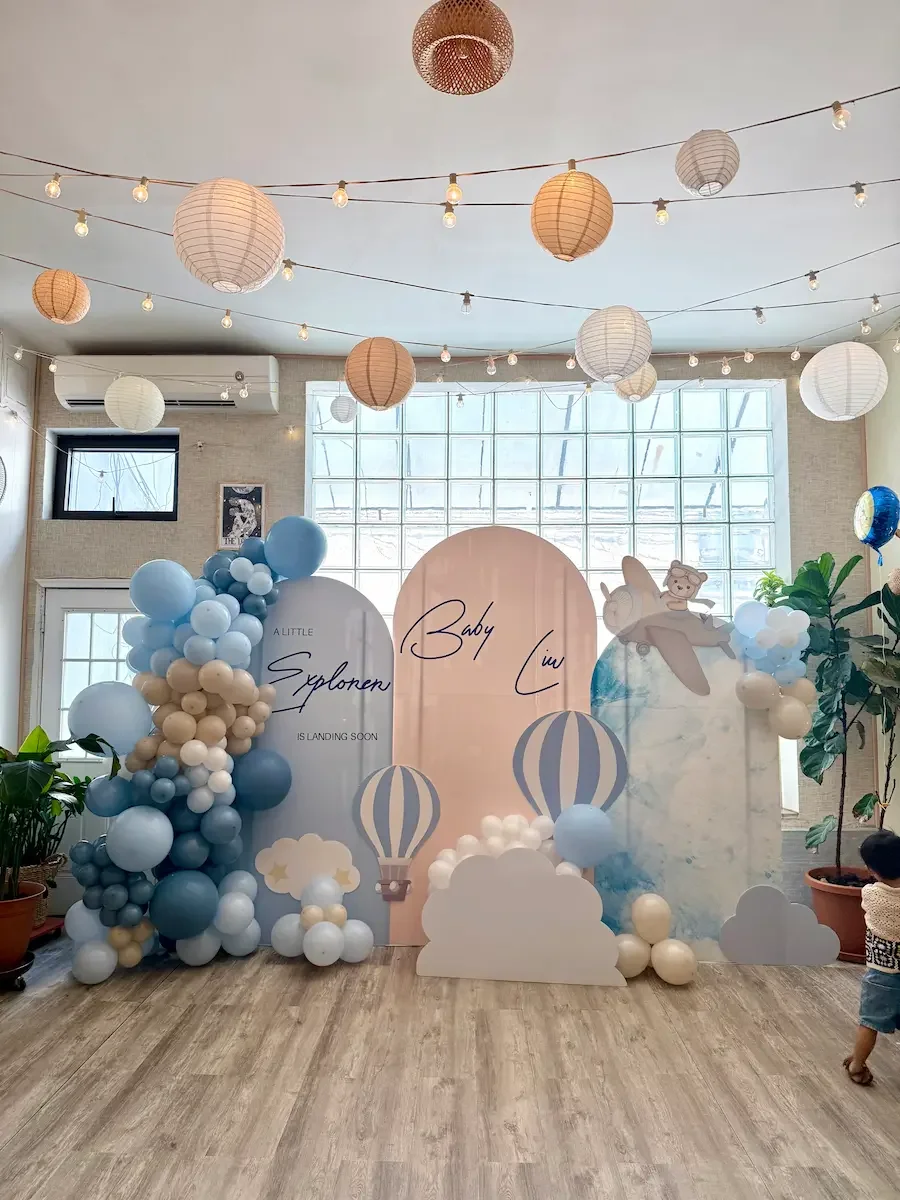 Blue balloon arch and hot-air-balloon backdrop set up for a baby shower at Bat Haus in Williamsburg, Brooklyn.