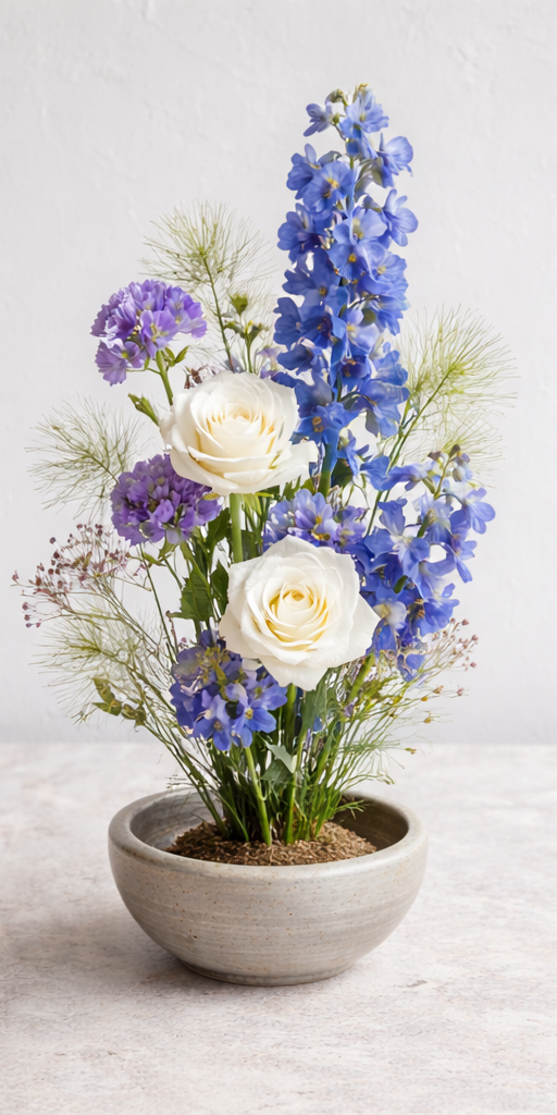 A Japanese ikebana floral arrangement in a handmade ceramic bowl, featuring seasonal blooms in coral, burgundy, and blush tones. Designed for styled event tables at Bat Haus in Brooklyn, this minimalist centerpiece brings natural elegance and intenti