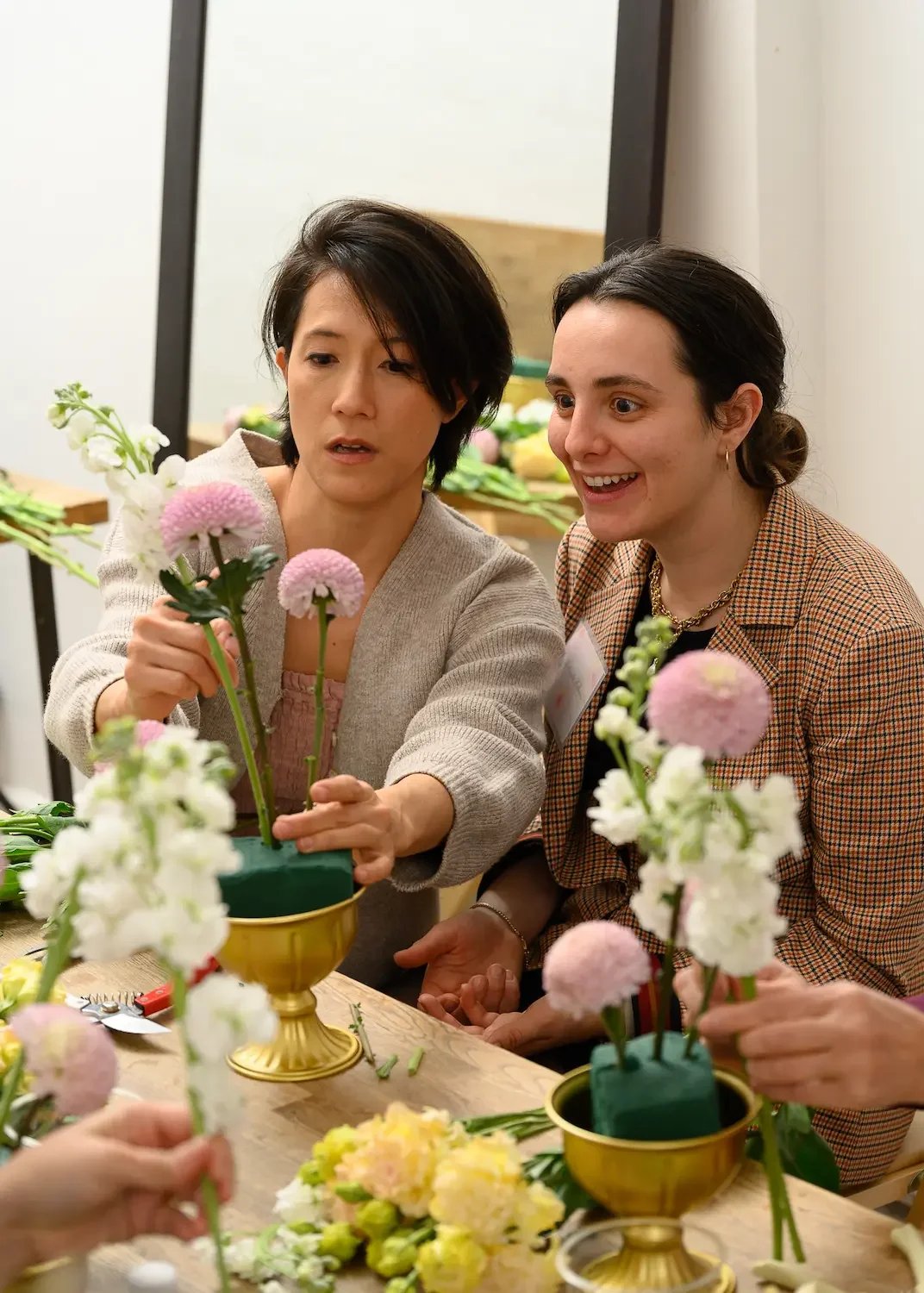 Two colleagues arranging flowers together at a corporate floral team-building workshop at Bat Haus in Williamsburg, Brooklyn.