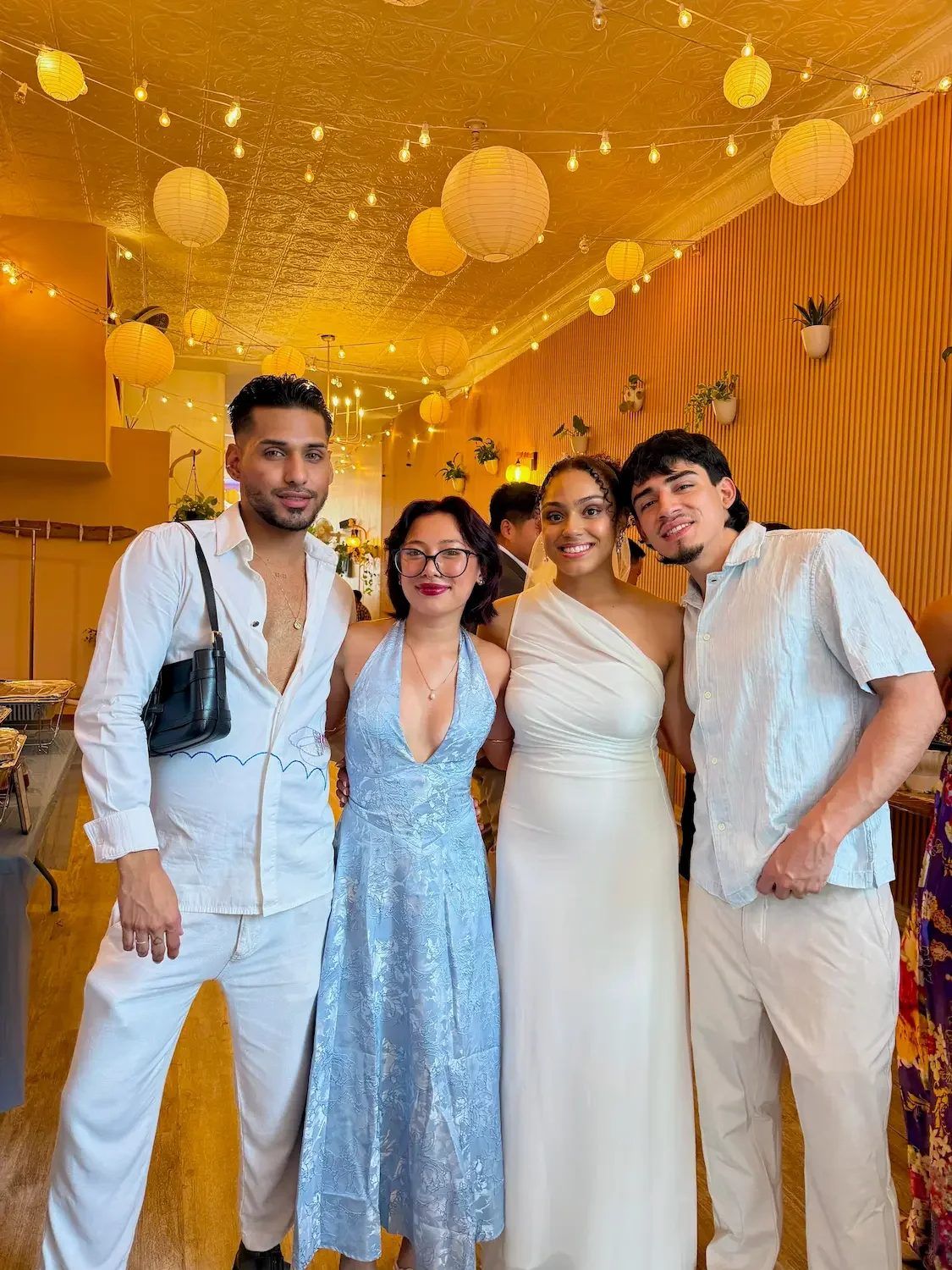 Wedding guests in summer whites and blues under paper lanterns and string lights at Bat Haus, an intimate wedding venue in Williamsburg, Brooklyn