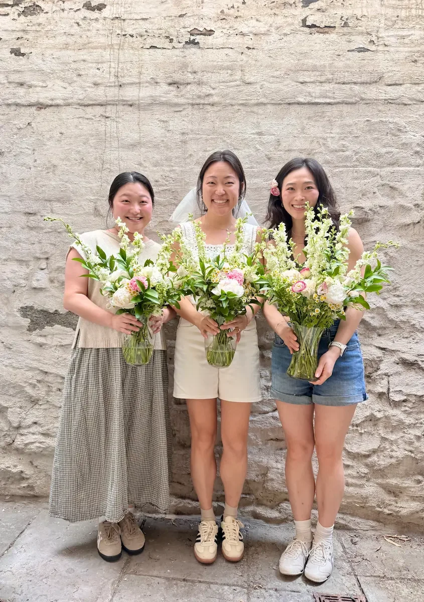 A bride in a veil with friends holding bouquets at her bridal shower at Bat Haus in Williamsburg, Brooklyn.