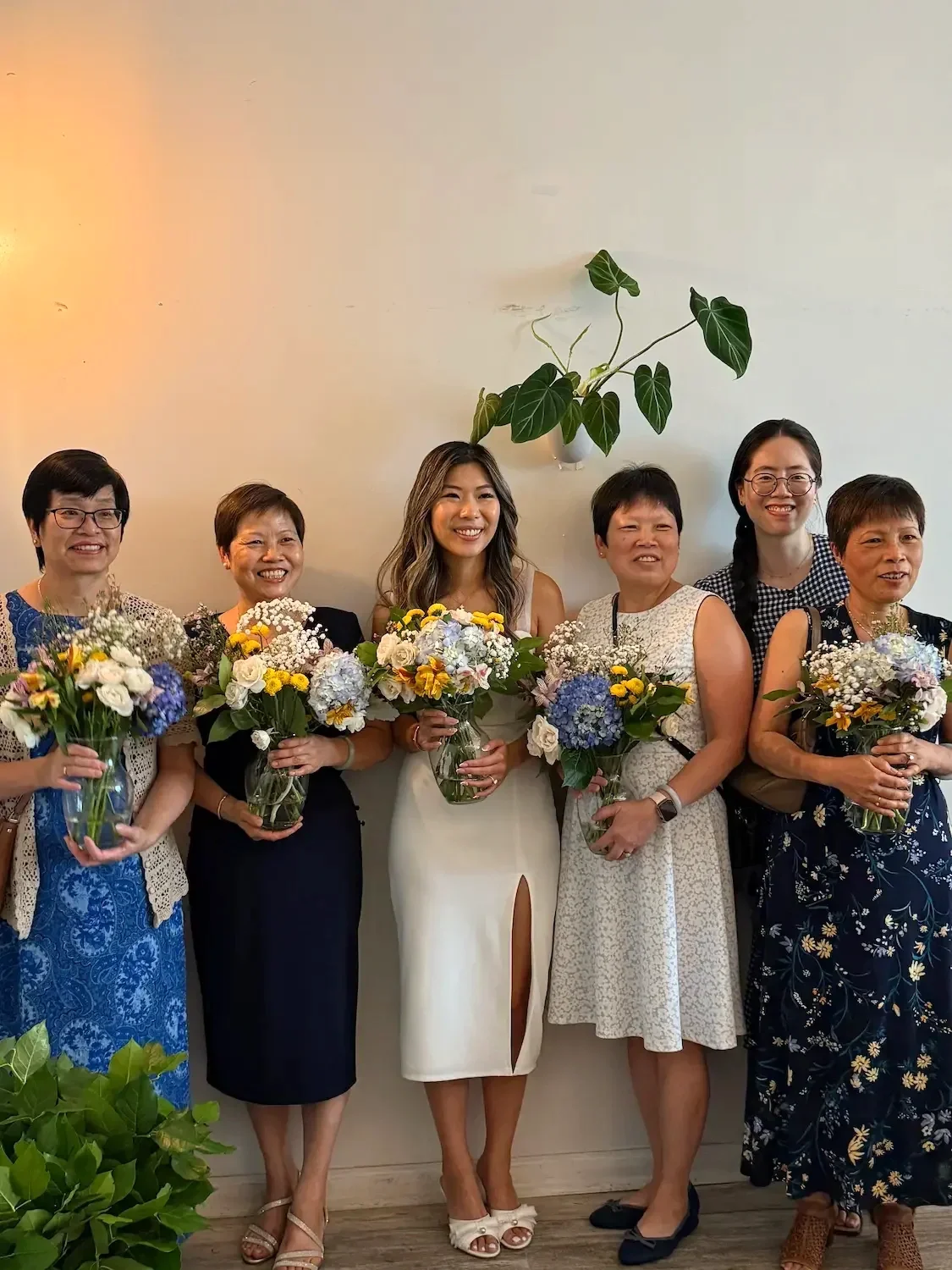 A multigenerational family holding bouquets at a bridal shower floral workshop at Bat Haus in Williamsburg, Brooklyn.