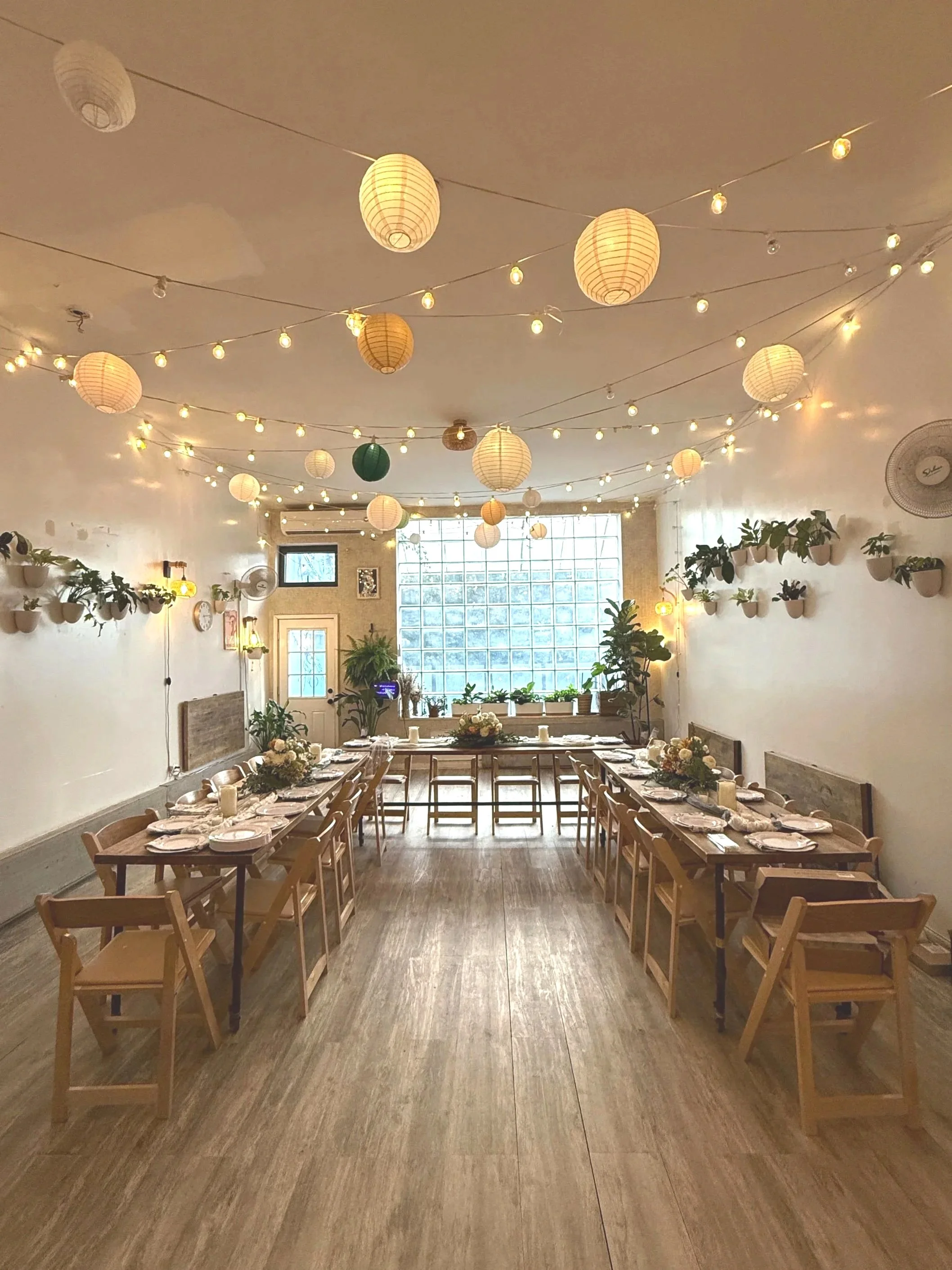 Fully styled dining setup at Bat Haus featuring bud vase florals, wooden tables, chairs, and warm string lighting, included in the Styled Package for weddings and celebrations.