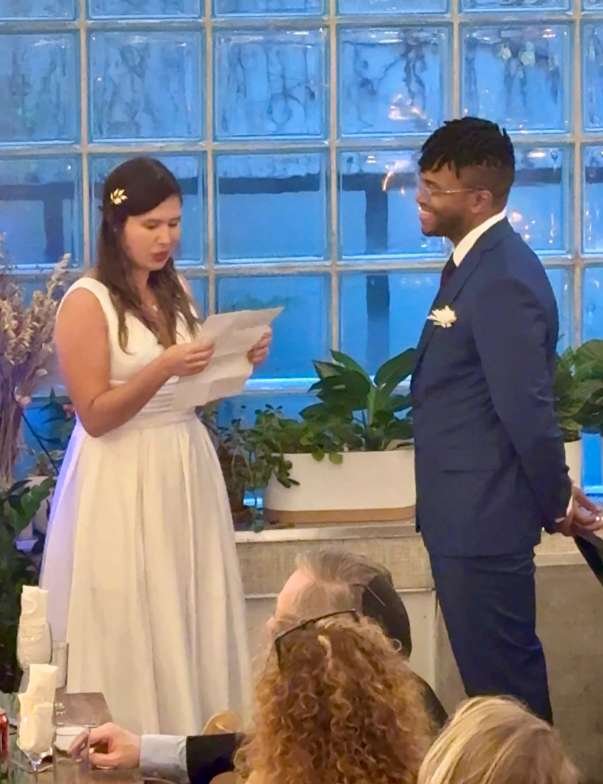Couple exchanging vows during a micro-wedding ceremony at Bat Haus in Brooklyn, surrounded by natural light, greenery, and an intimate gathering of loved ones.