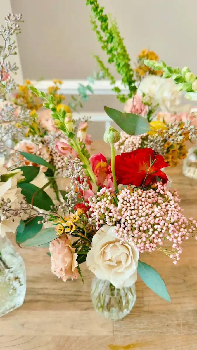 Coral and blush bud vase arrangement with roses and eucalyptus, a seasonal table floral at Bat Haus in Brooklyn.