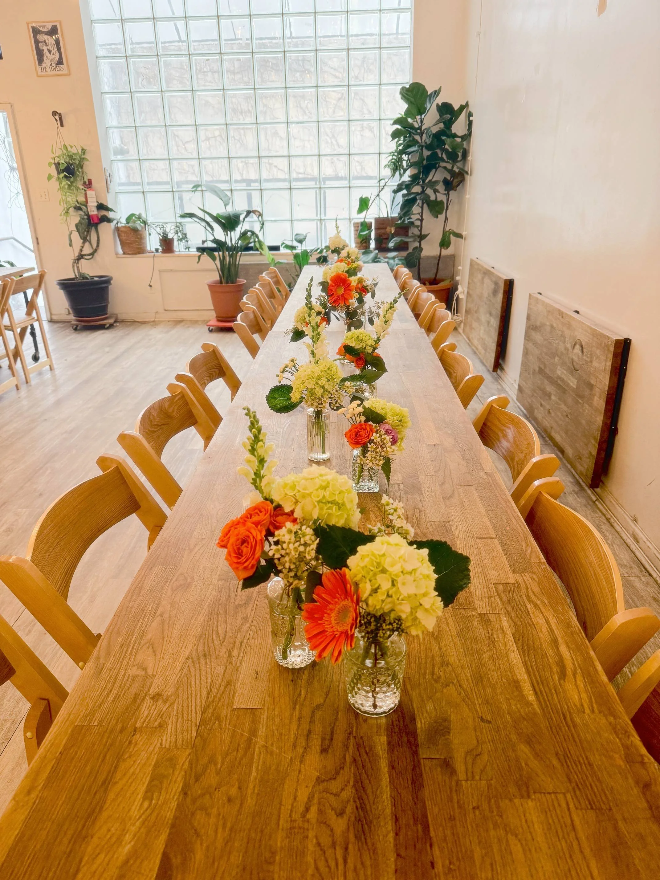 Long wooden table styled with multiple bud vase floral arrangements as part of the Bat Haus Styled Package, creating an effortless, ready-to-host event setup.