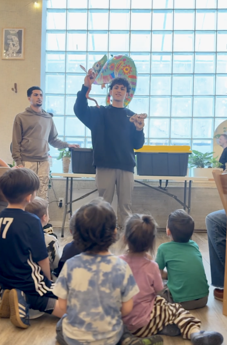 A magician entertaining children seated on the floor at a kids' birthday party at Bat Haus in Williamsburg, Brooklyn.