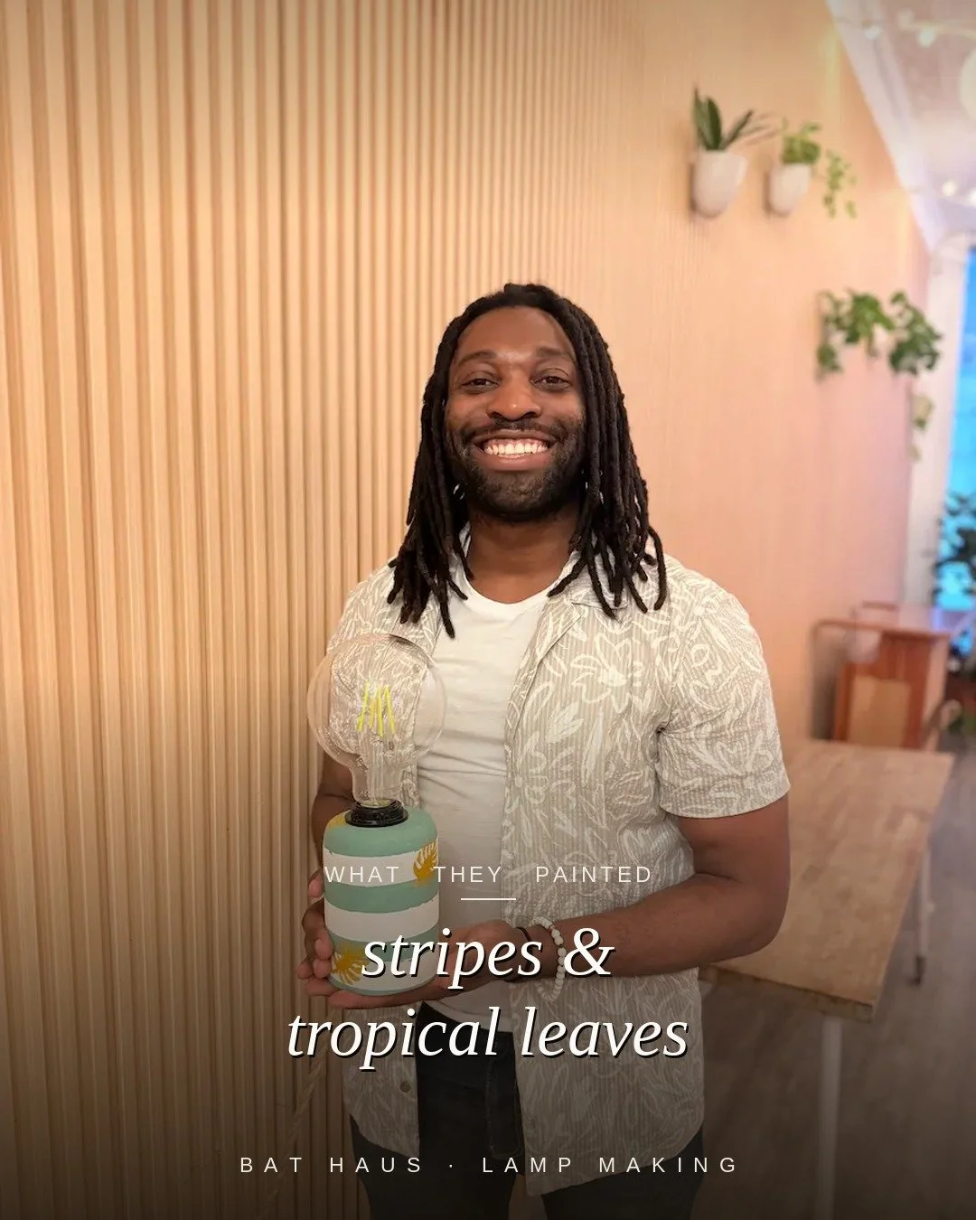 Guest holding a teal and white striped lamp accented with painted tropical leaves.