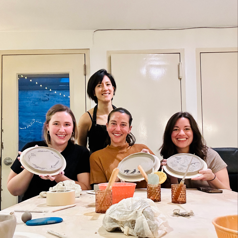 Natalie Chan with guests holding their handmade plates at a pottery class she leads at Bat Haus in Brooklyn.