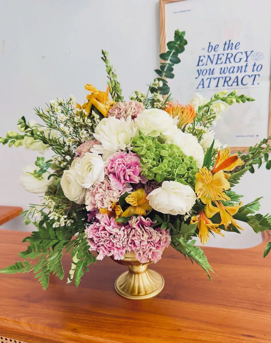 Signature floral arrangement included in the Styled package at Bat Haus in Brooklyn, featuring seasonal blooms in a gold pedestal vase.