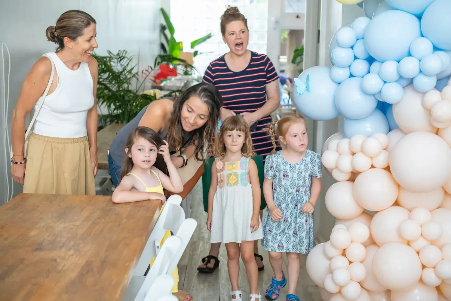 Kids birthday party place in Brooklyn at Bat Haus with a parent and child smiling during a decorated birthday celebration with balloons, tables, and party setup.