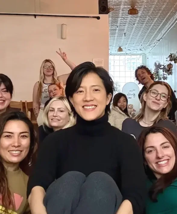 Bat Haus founder Natalie Chan seated with a corporate team during a group sound bath session in the Brooklyn event space.