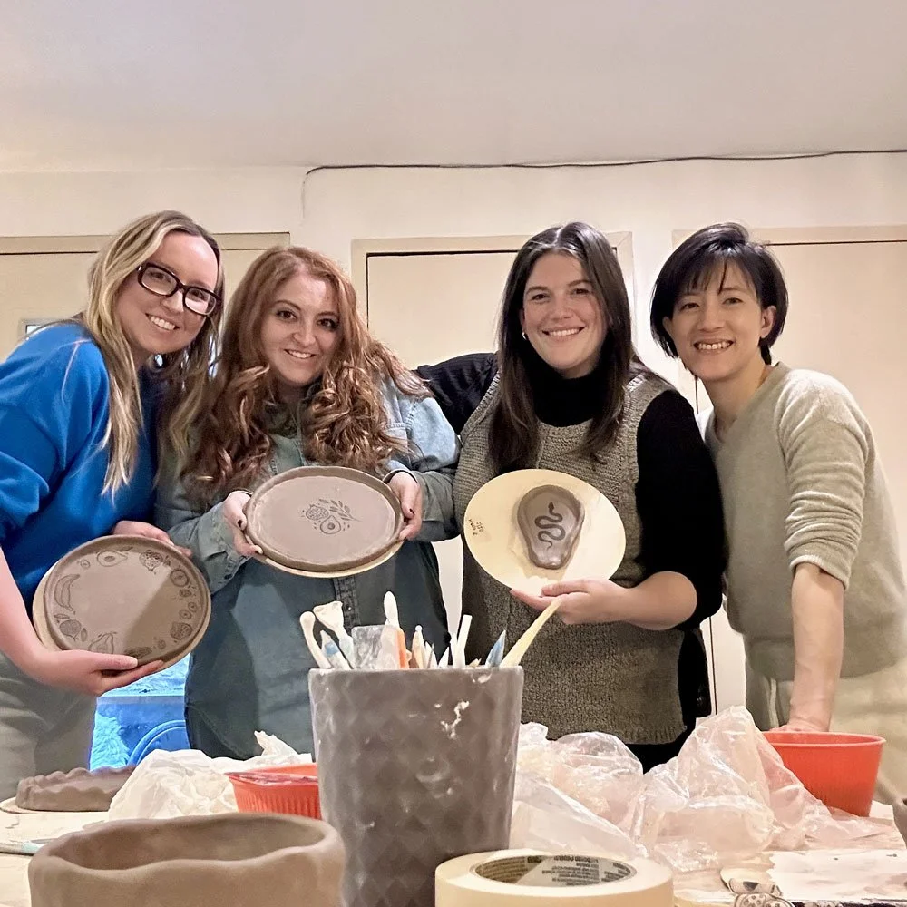 A small group showing their handmade clay pieces at a private pottery class at Bat Haus in Williamsburg, Brooklyn.