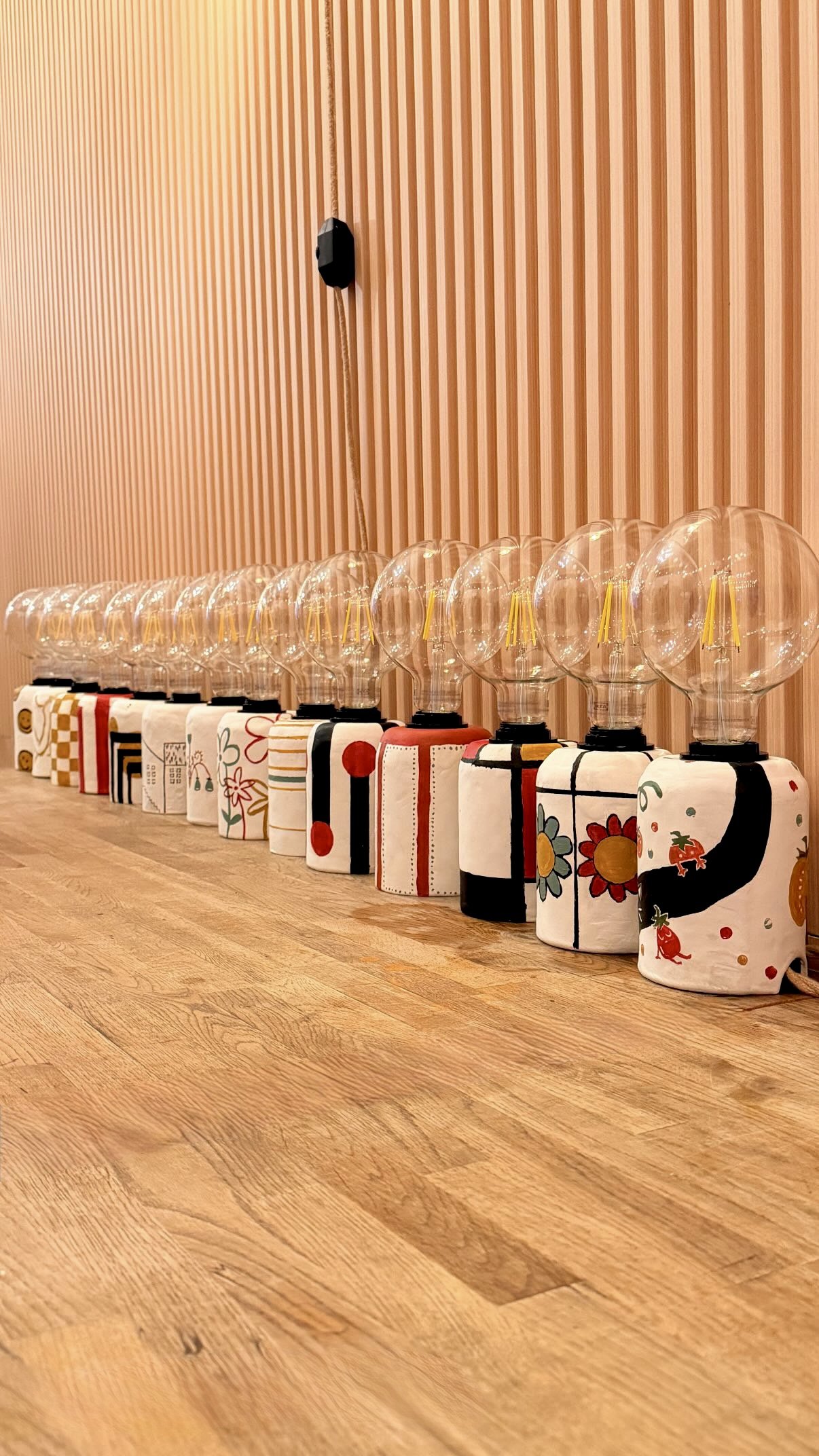 A row of colorful hand-painted lamps made by guests at a Bat Haus lamp-making workshop in Williamsburg, Brooklyn.