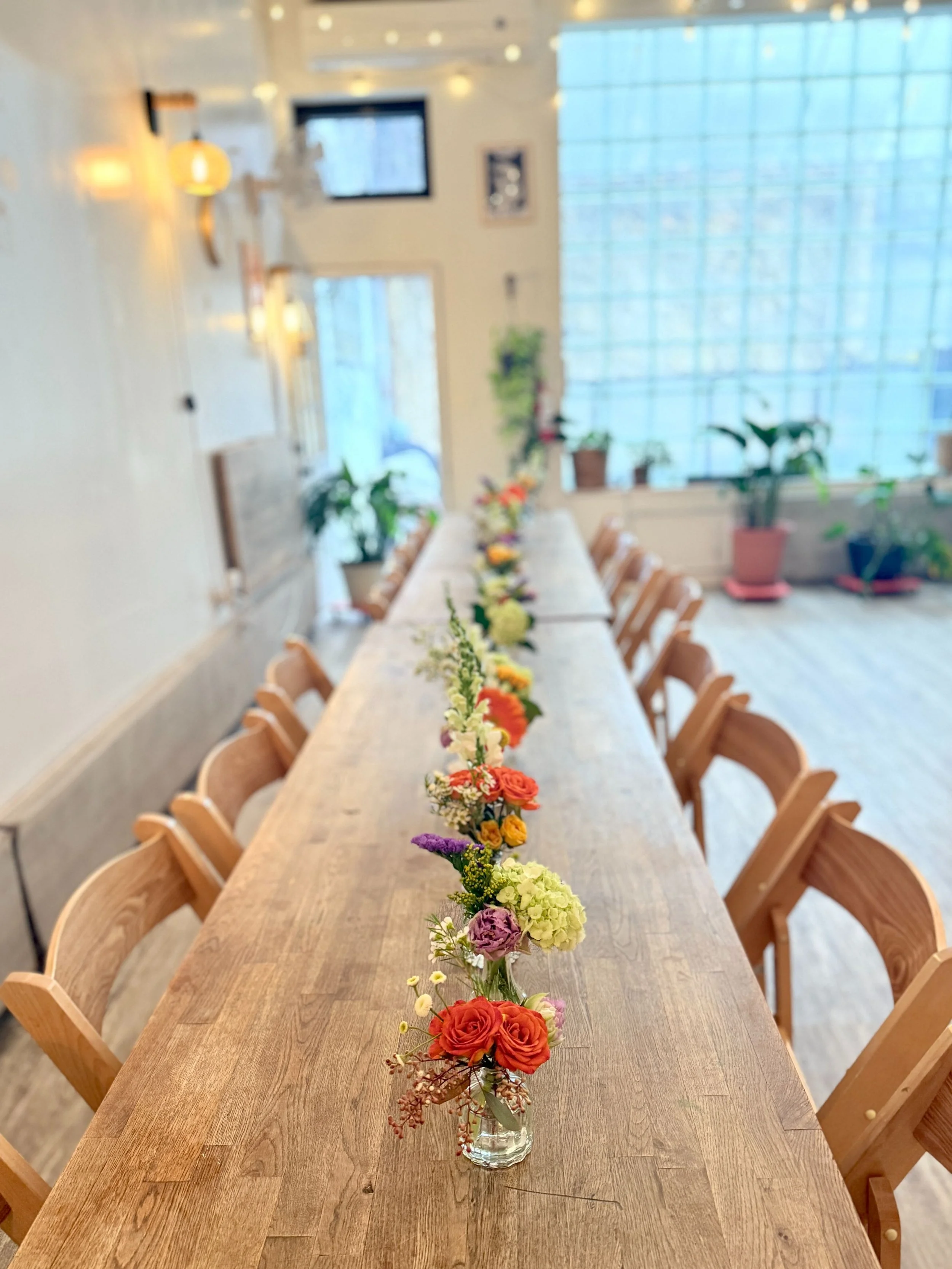 A continuous line of mini arrangements running the length of the table—color pops repeating for a cohesive, modern look.