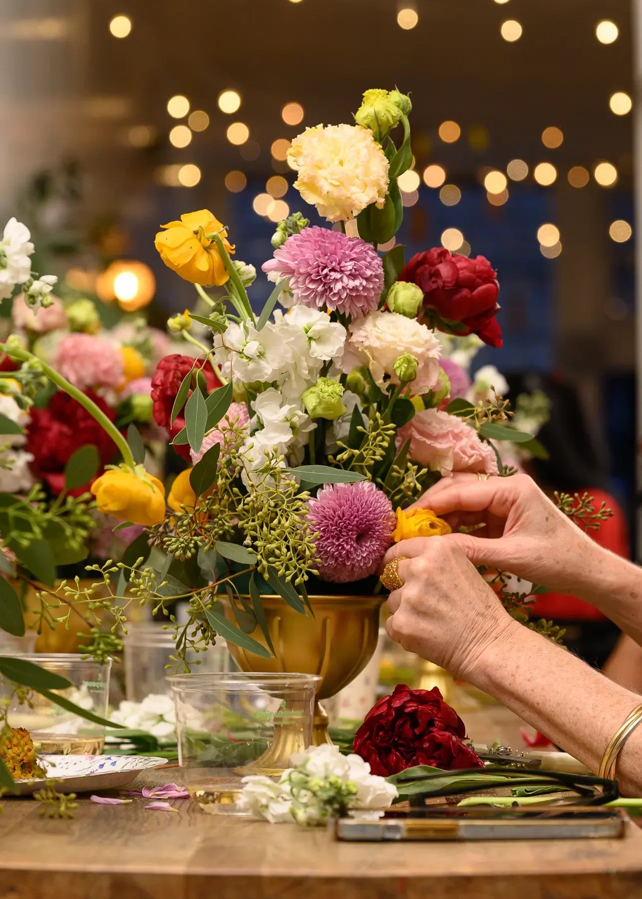 A colorful floral arrangement in a gold vase being built at a bridal floral workshop at Bat Haus in Williamsburg, Brooklyn.