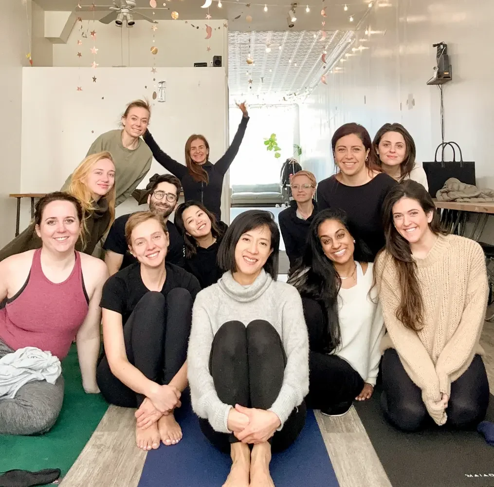 Group sound bath session in Brooklyn NYC with participants seated on yoga mats in a bright studio space for relaxation and team connection