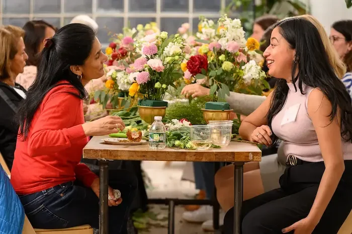 Colleagues arranging colorful flower centerpieces together during a corporate floral workshop at Bat Haus event space in Williamsburg Brooklyn.