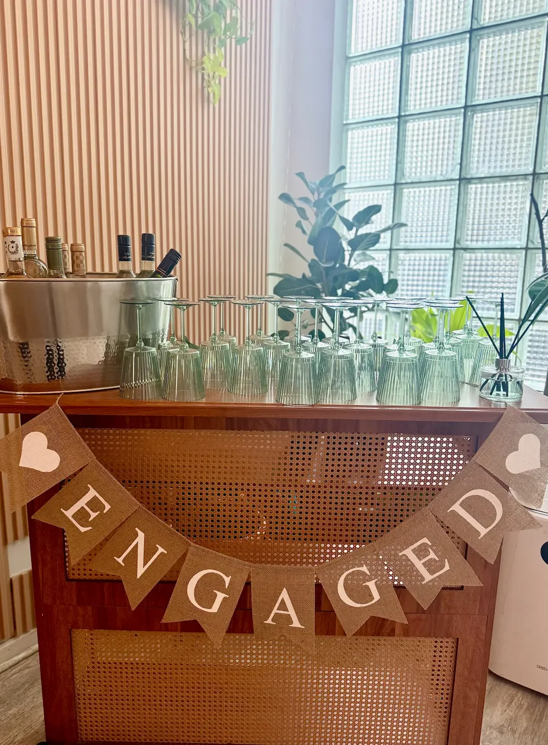 An 'Engaged' banner over a self-serve BYO bar with glassware at an engagement party at Bat Haus in Brooklyn.