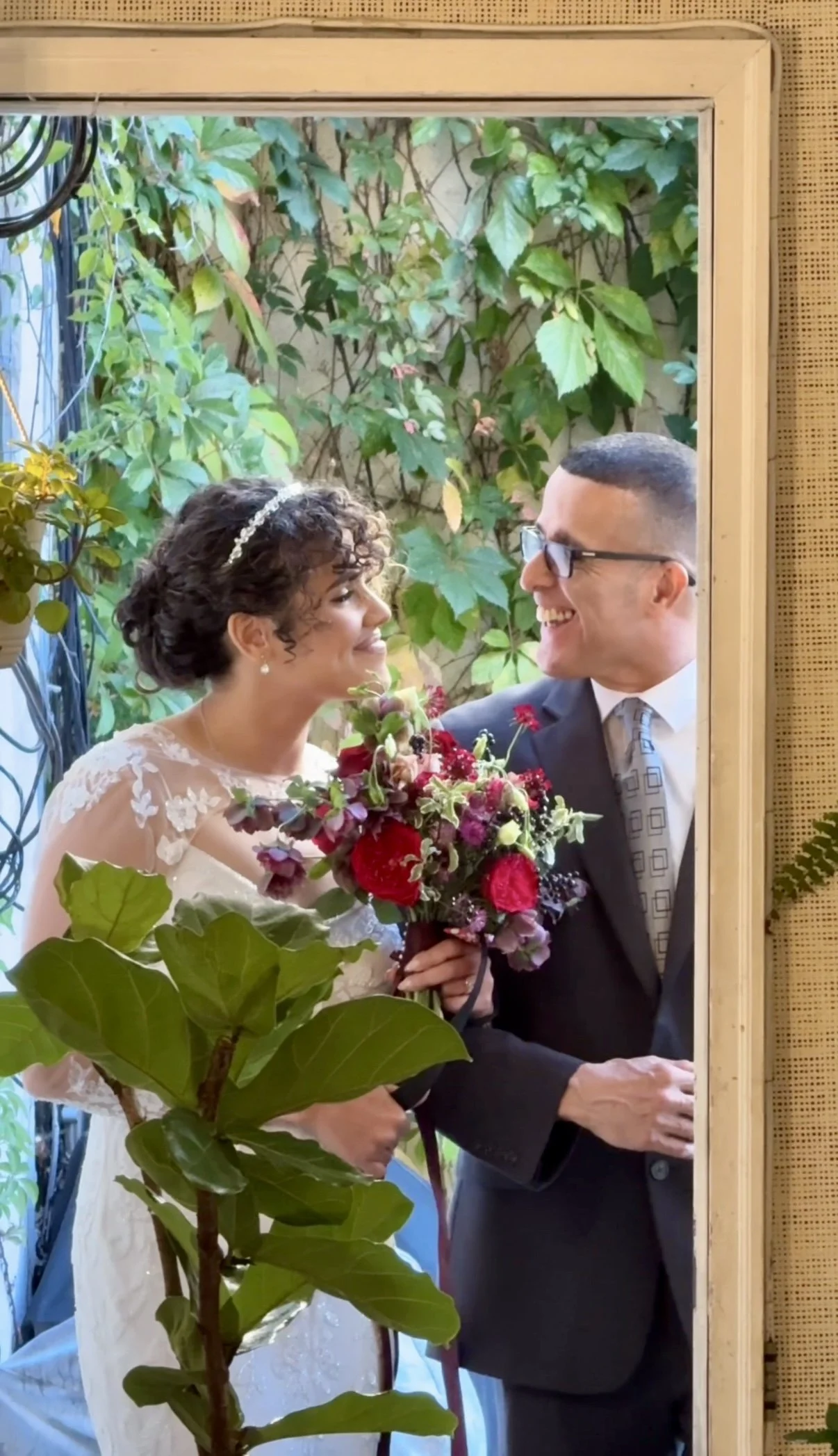 Newly married couple sharing a joyful moment during an intimate wedding at Bat Haus in Brooklyn, surrounded by lush greenery and floral details.