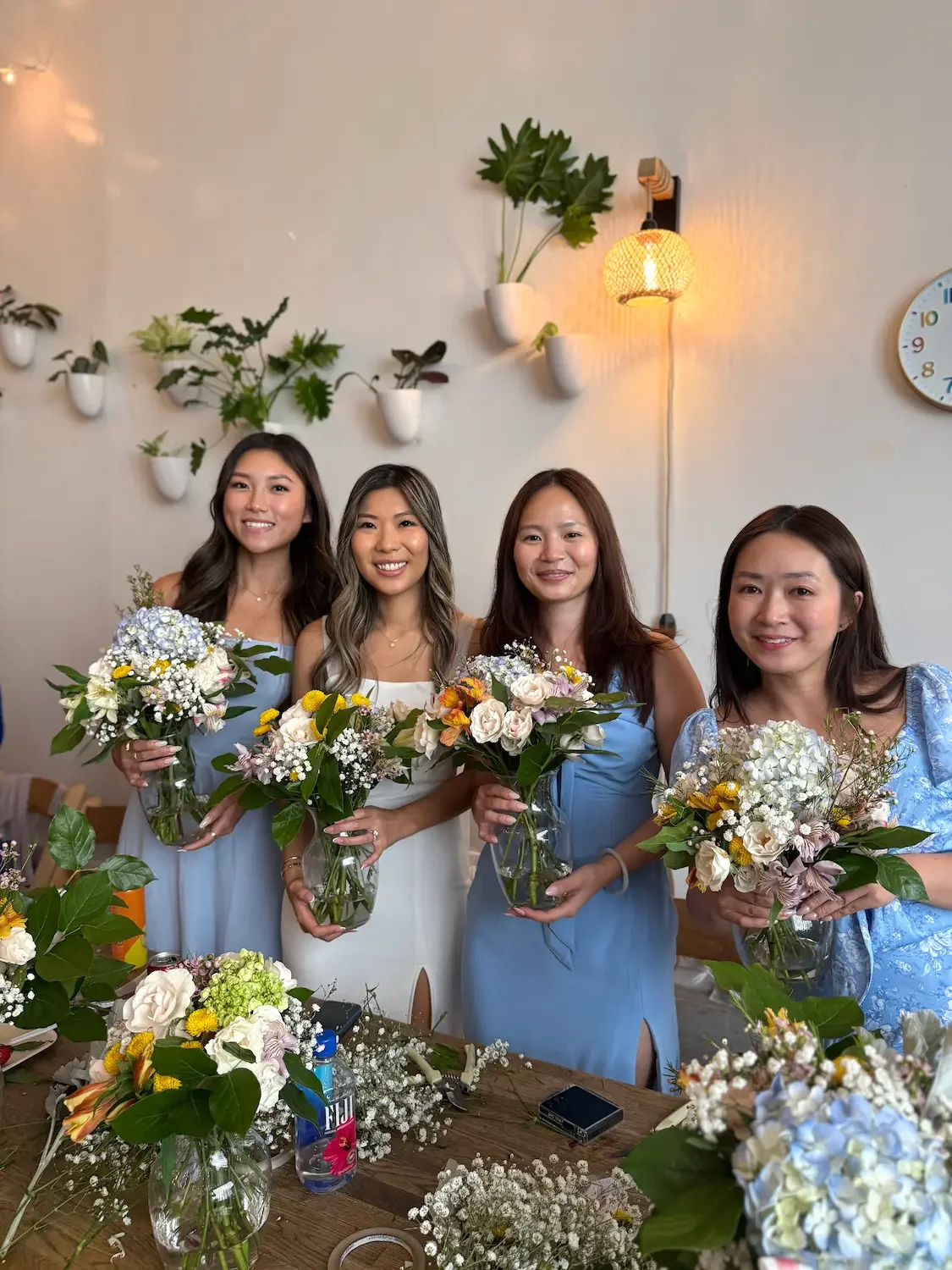 Bridesmaids in blue holding the floral arrangements they made at a bridal shower workshop at Bat Haus in Williamsburg, Brooklyn.