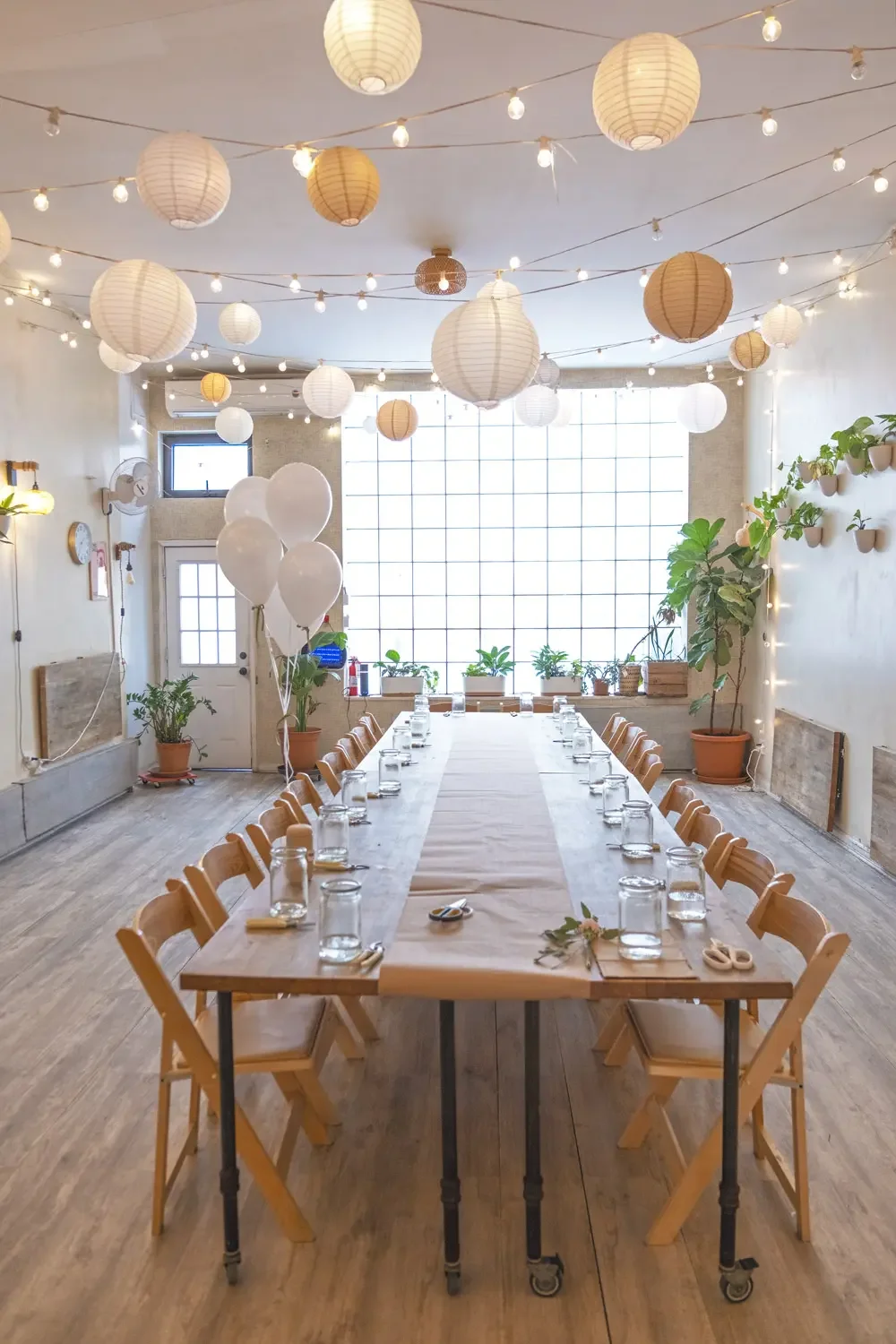 Bat Haus event space set with a long banquet table, white balloons, paper lanterns, and string lights in Williamsburg, Brooklyn