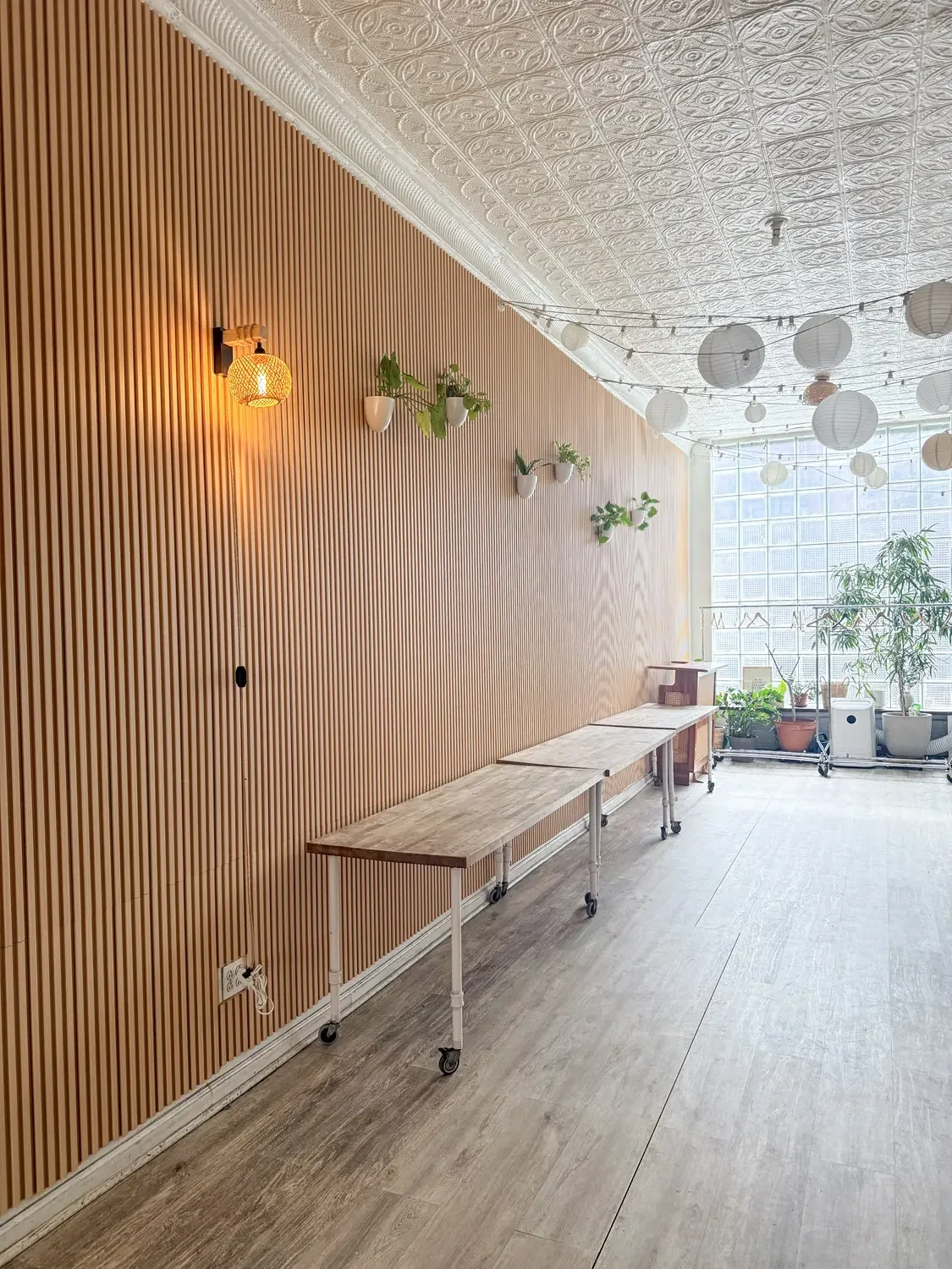 The light-filled main room with a wood-slat wall and rolling tables, set up for a corporate offsite at Bat Haus in Brooklyn.