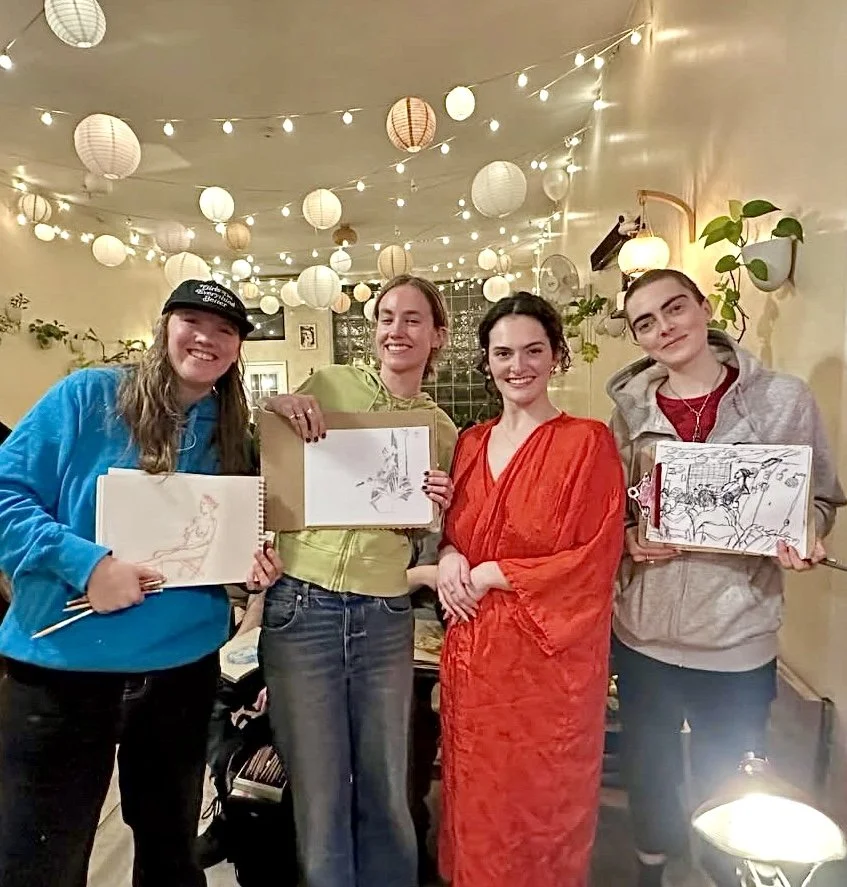Drink n Draw participants at Bat Haus Brooklyn smiling and holding their figure drawing sketches after a live model session, a fun midweek art event and drawing class in Brooklyn