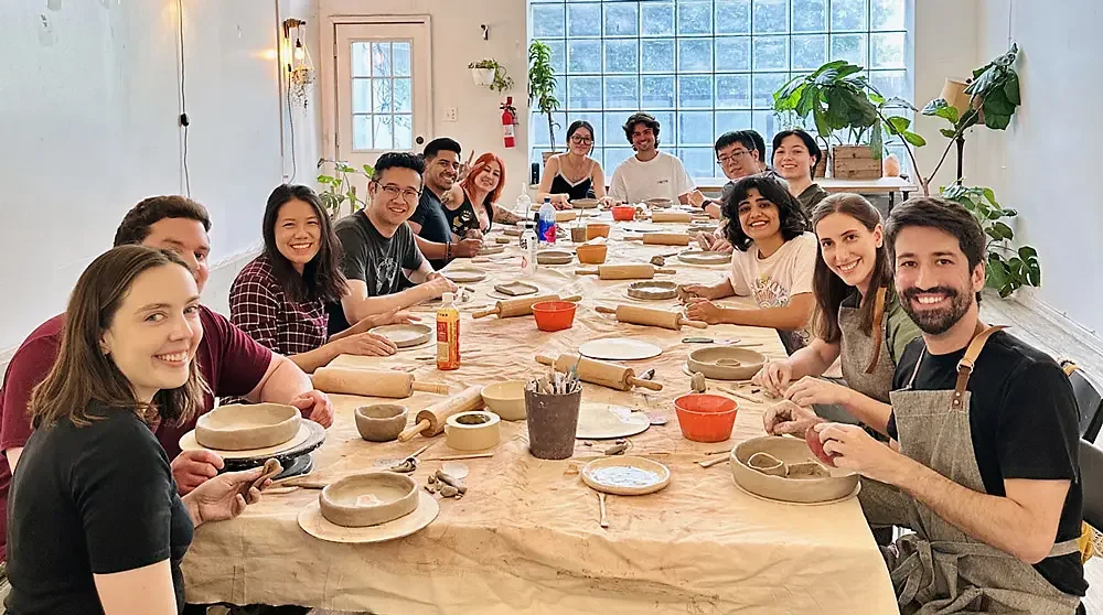 A corporate team around a long table at a hand-building pottery team-building class at Bat Haus in Brooklyn.