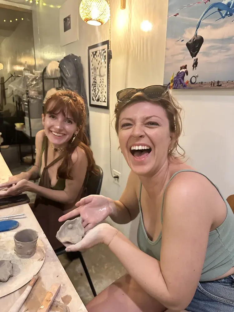 private pottery class brooklyn at bat haus two guests smiling while hand building clay pieces at a pottery workshop table