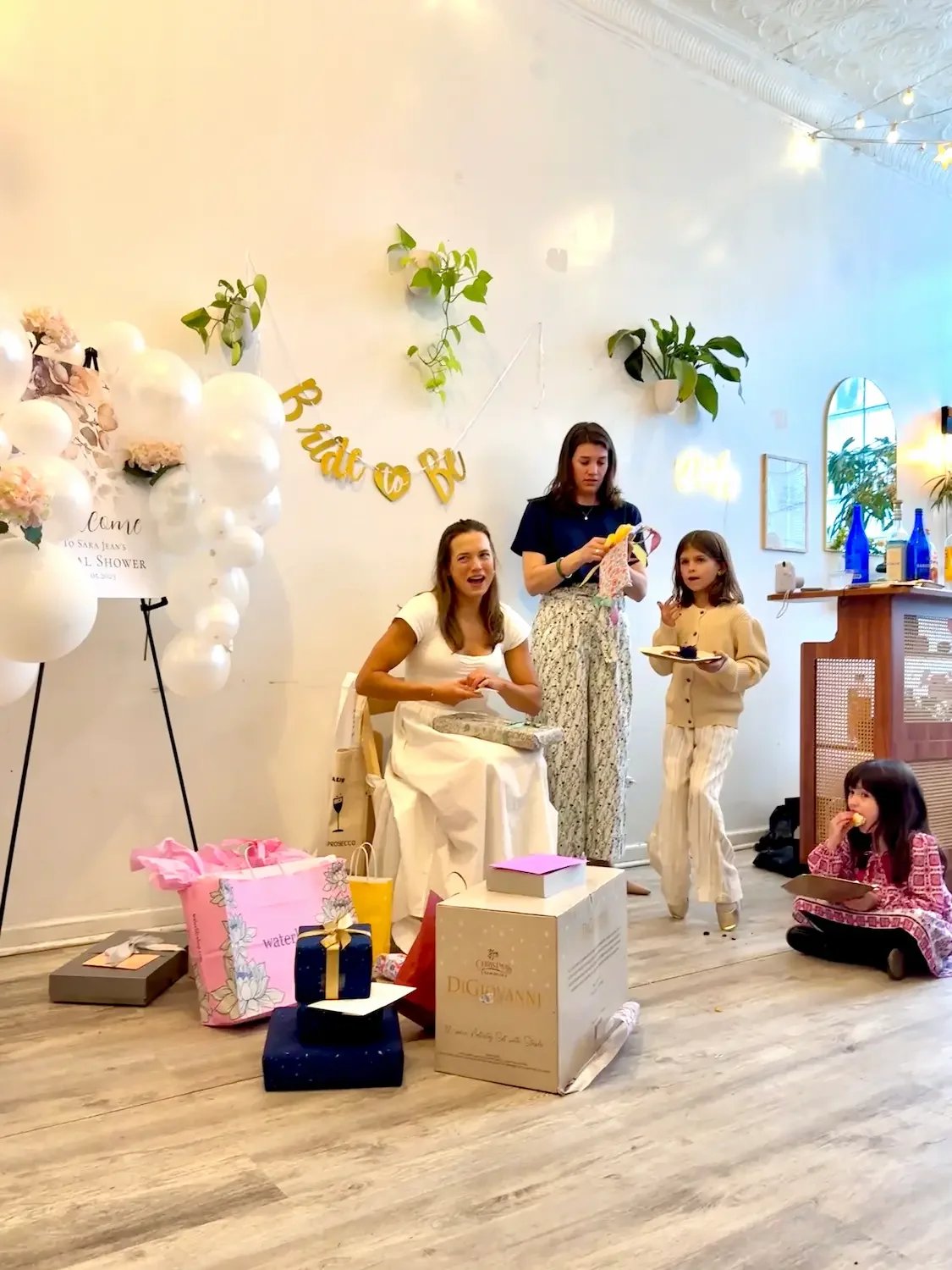 A bride opening gifts beside a balloon backdrop at a bridal shower at Bat Haus in Williamsburg, Brooklyn.