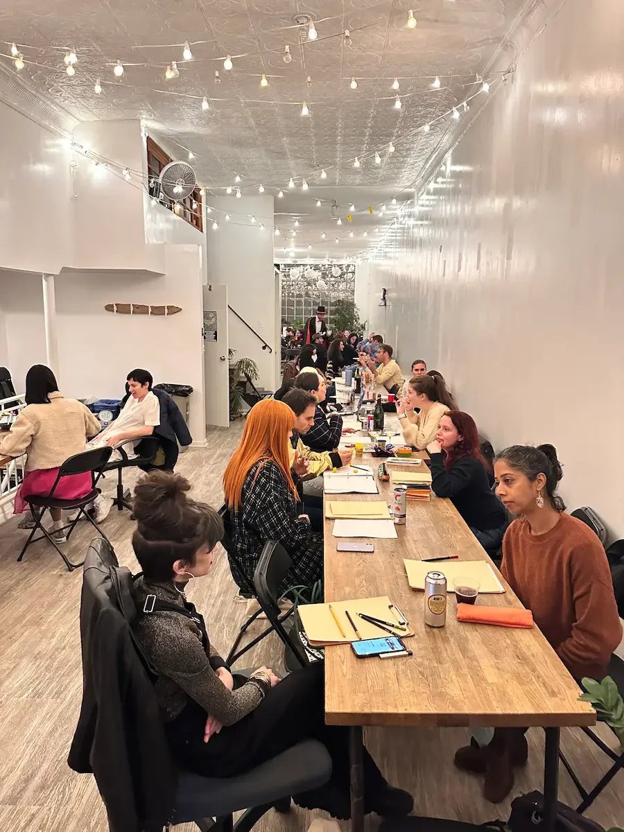 Corporate team seated at long wooden tables during an offsite meeting at Bat Haus in Brooklyn demonstrating collaborative table configuration.