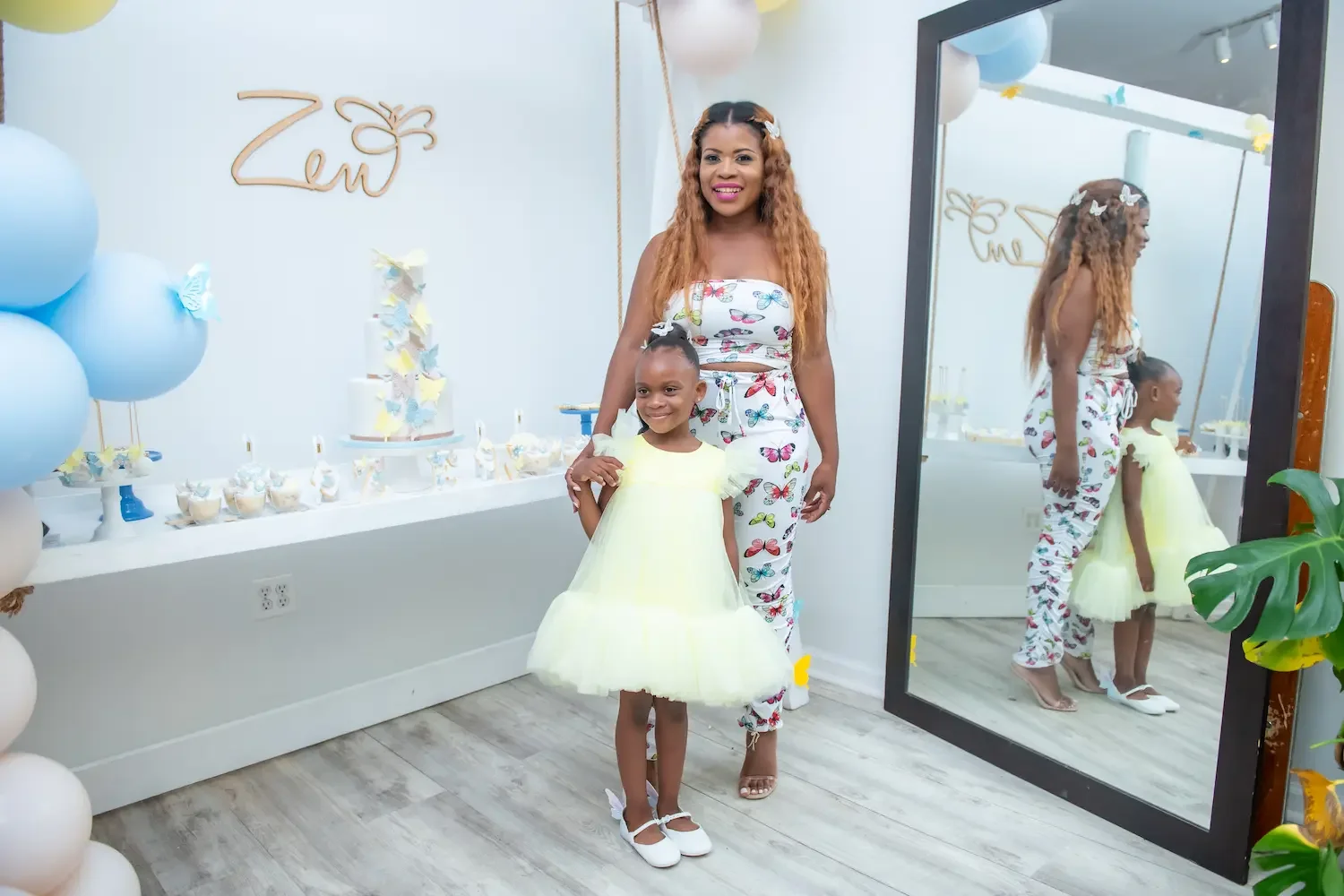 Kids birthday party place in Brooklyn at Bat Haus with a child and parent standing near a butterfly themed birthday dessert table and balloon decorations.