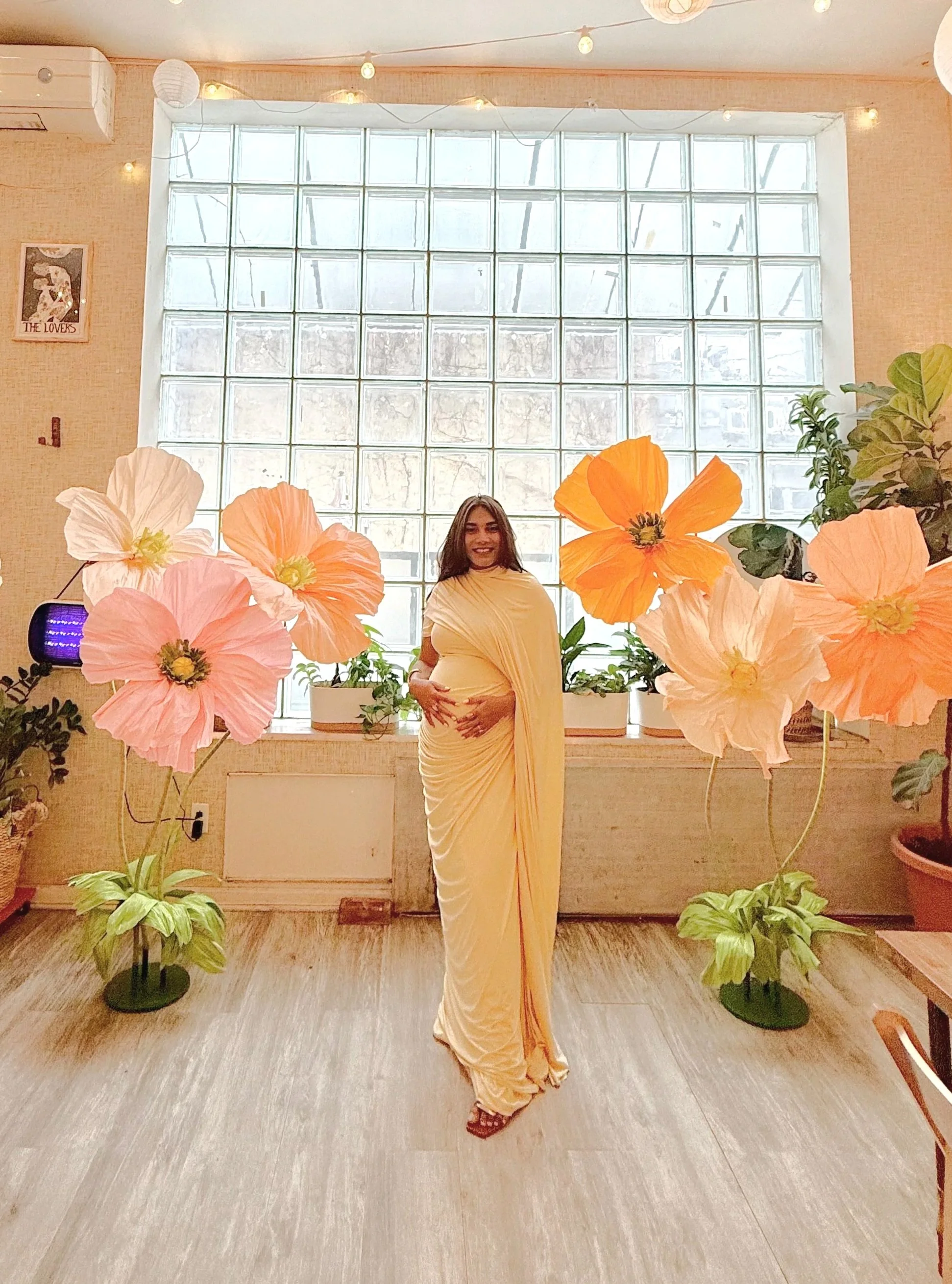 Baby shower at Bat Haus with paper flower decor in the background with large window wall