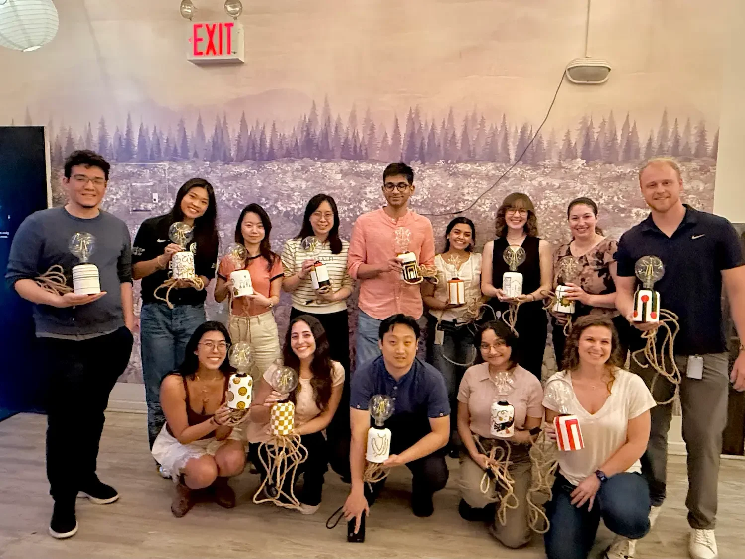 A group of participants from Bat Haus' lamp making workshop in Brooklyn, holding their finished lamps ready to take home.