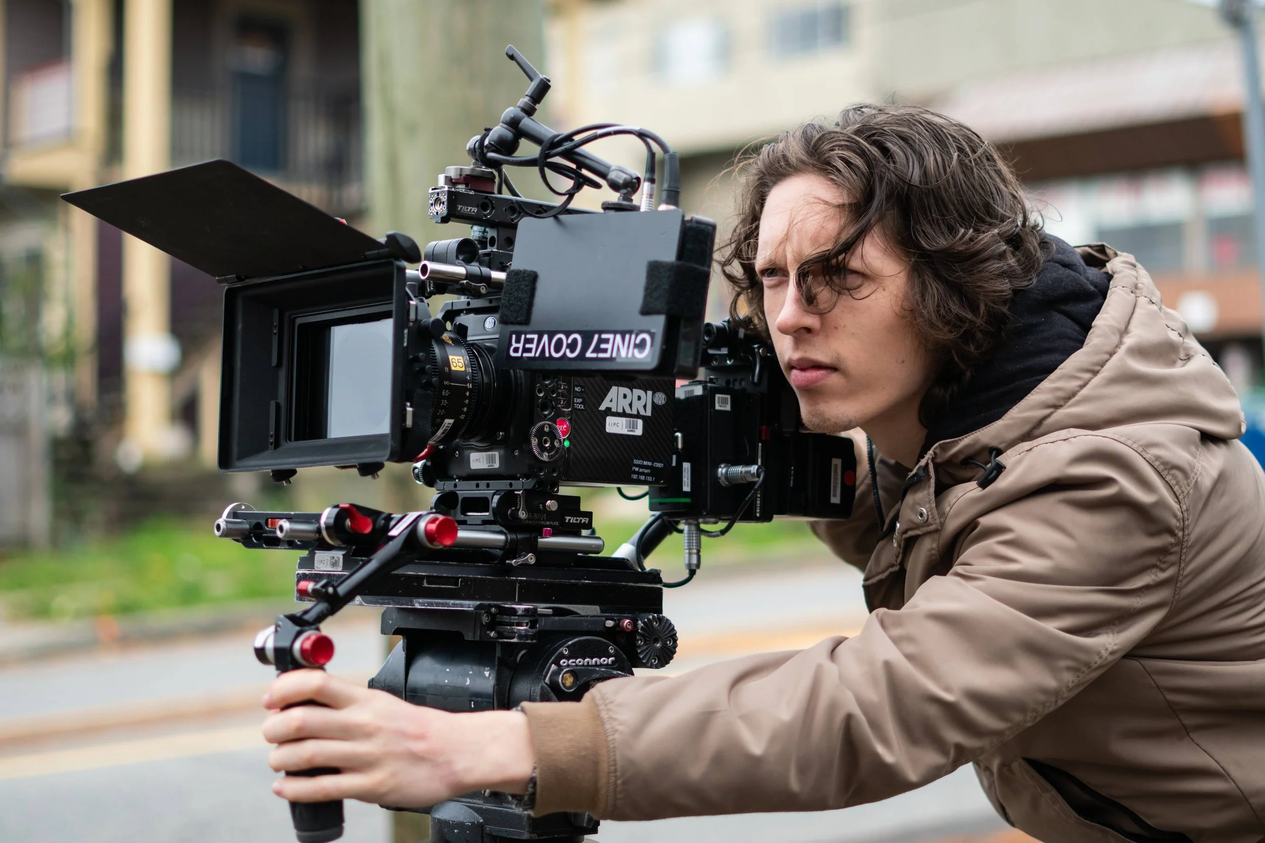 Young man operating professional ARRI film camera outdoors on a city street.
